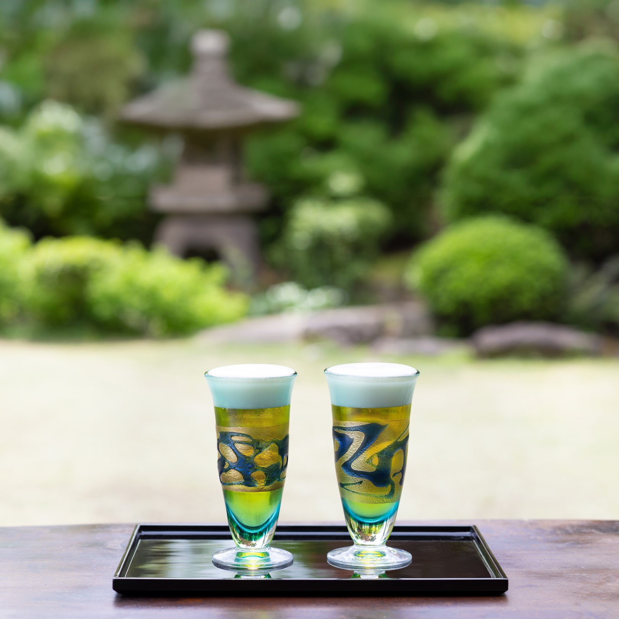 津軽びいどろ 金彩碧瑠璃 ピルスナーペアセット ビールグラスがのせられたおぼんが庭先に置かれている画像