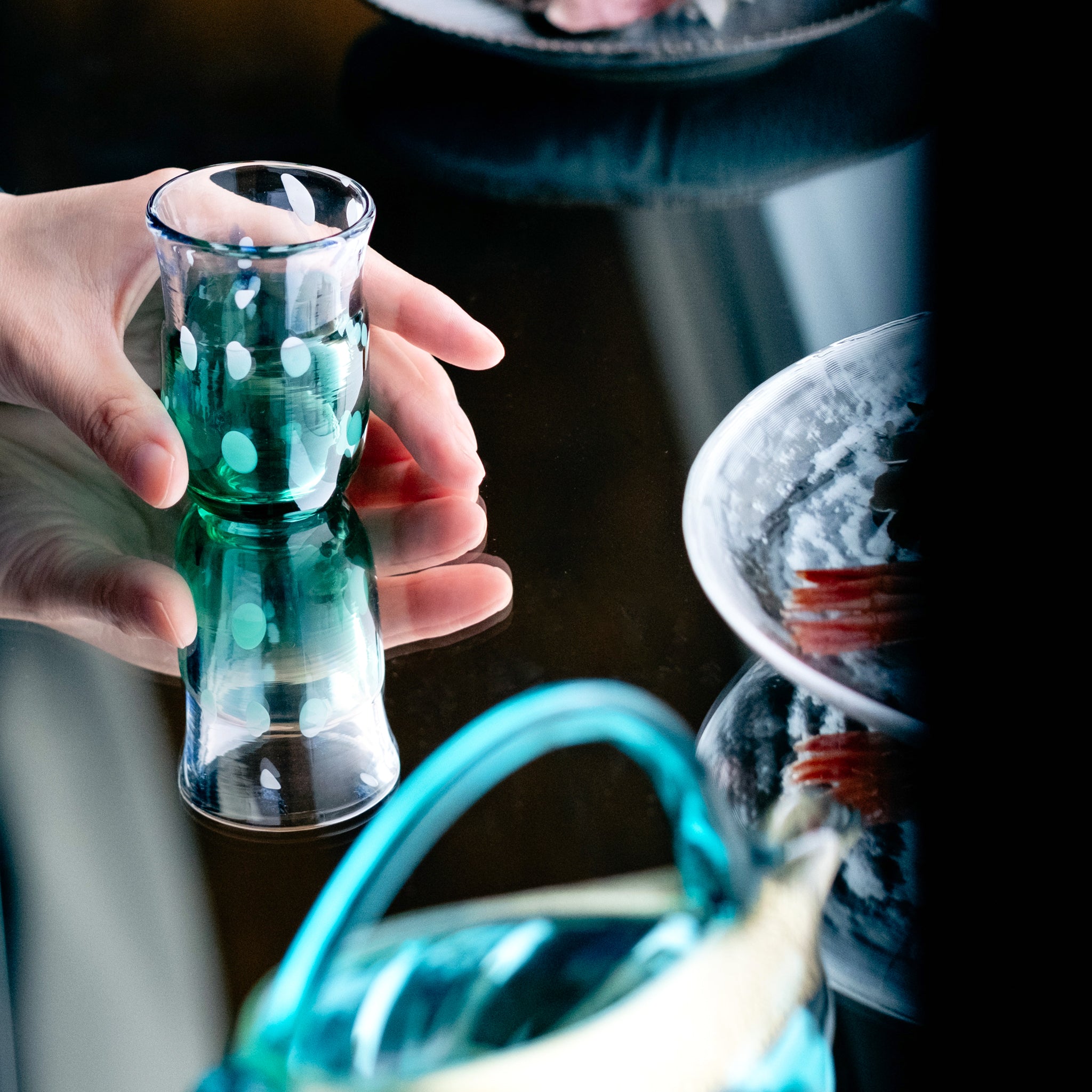 津軽びいどろ 盃12ヶ月コレクション 6月梅雨晴 食卓に並ぶ盃を手でつかんでいる画像