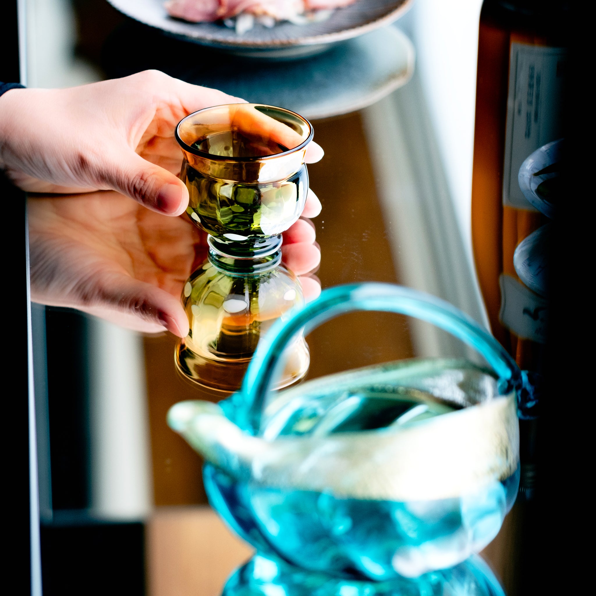 津軽びいどろ 盃12ヶ月コレクション 9月月見 食卓に並ぶ盃を手でつかんでいる画像