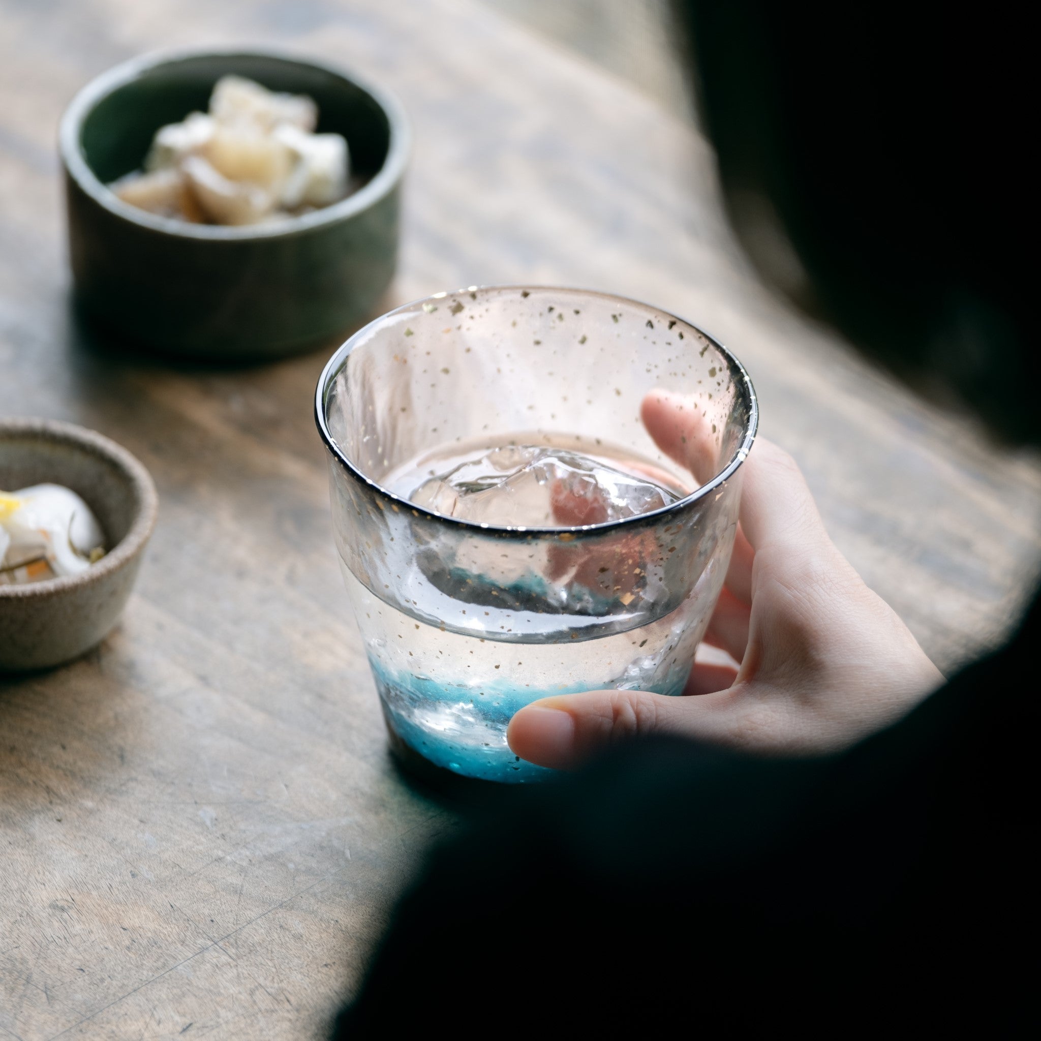 津軽びいどろ 氷華 金彩ロックグラス碧 水が入ったグラスを手でつかんでいる画像