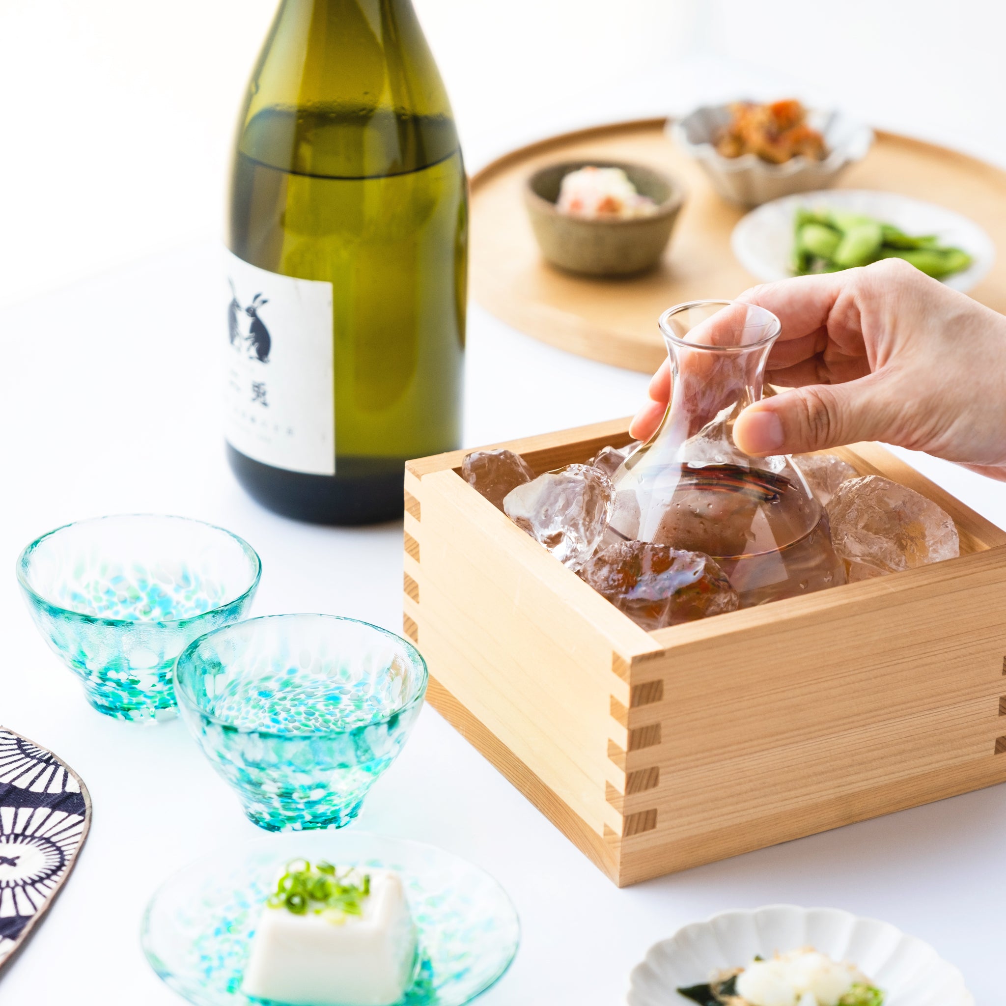 津軽びいどろ 酒器 みずばしょう酒器セット 食卓に並ぶ盃と氷で冷やしている徳利の画像