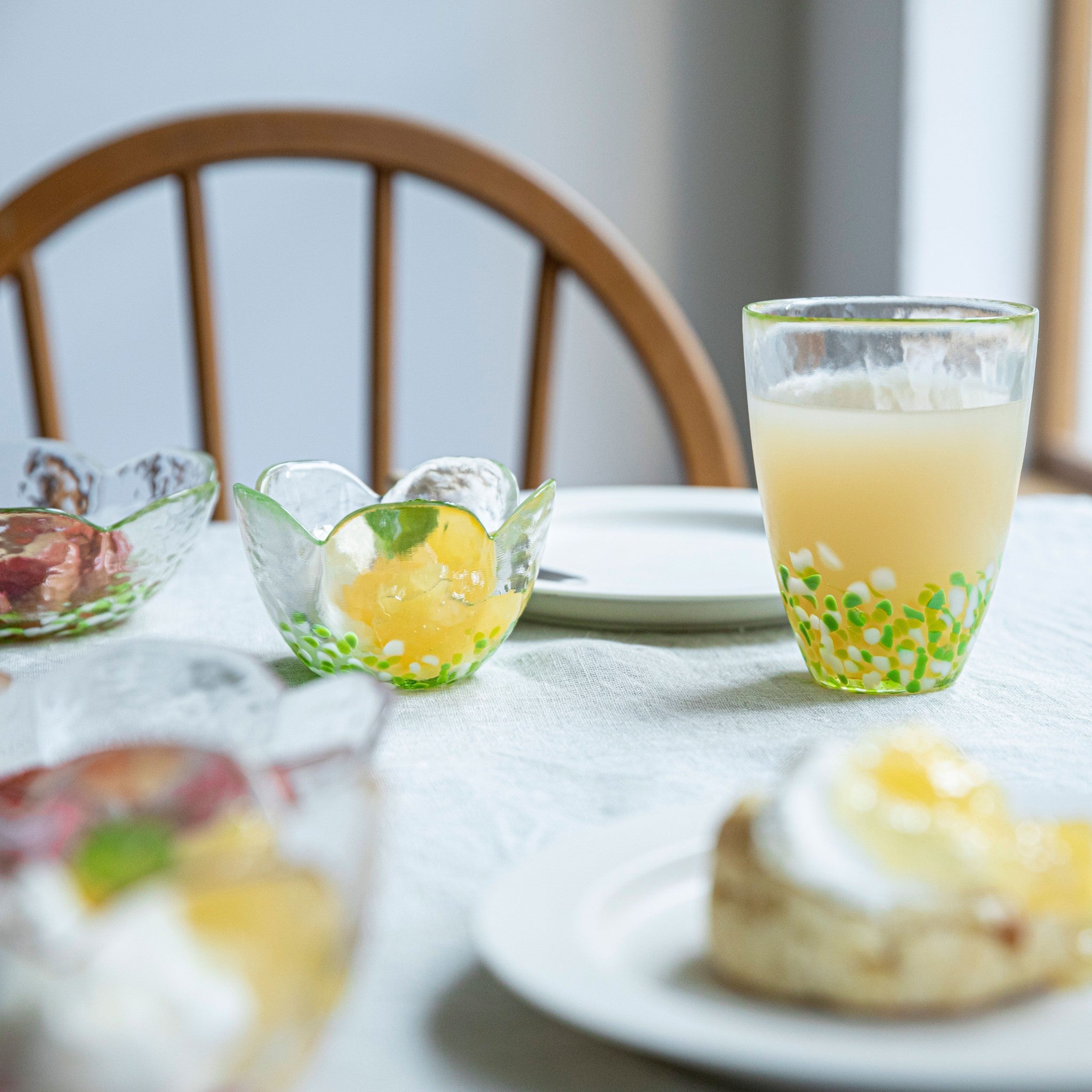 津軽びいどろ 津軽自然色りんご あおりんごタンブラー 食卓にグラスやガラスの器が並んでいる画像