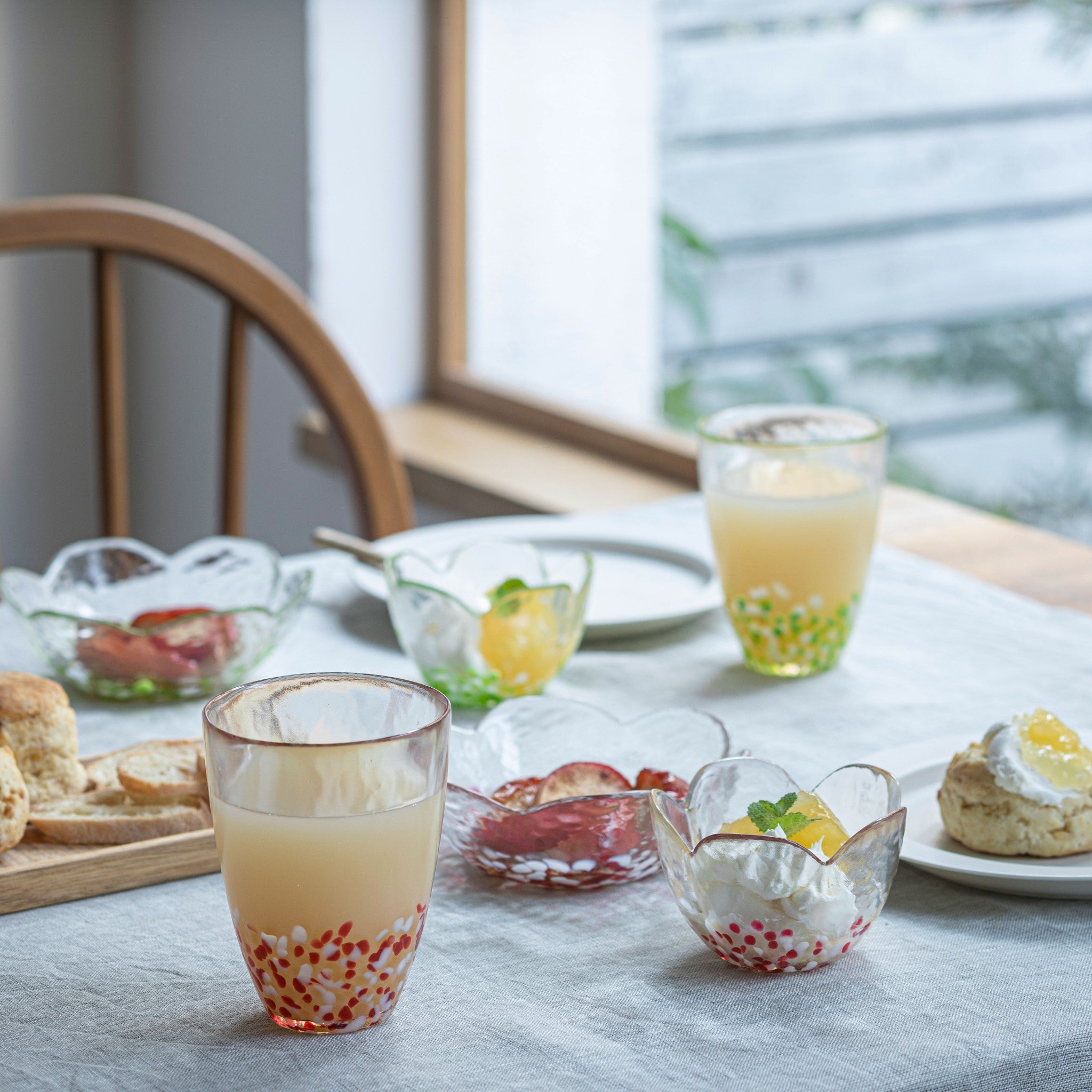 津軽びいどろ 津軽自然色りんご あおりんごタンブラー 食卓にグラスやガラスの器が並んでいる画像