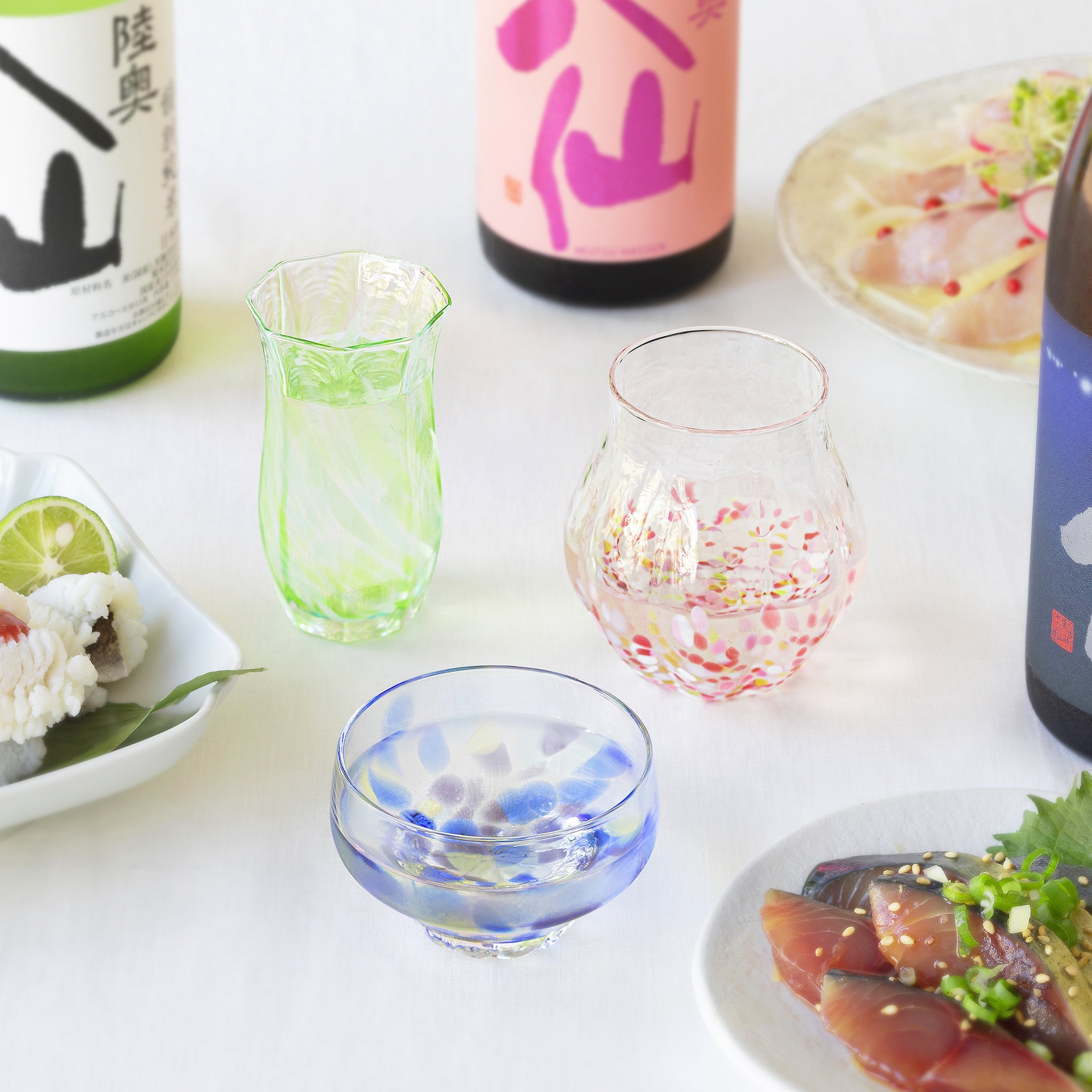 津軽びいどろ 酒器仙 海の灯 色違いの盃が食卓に並んでいる画像