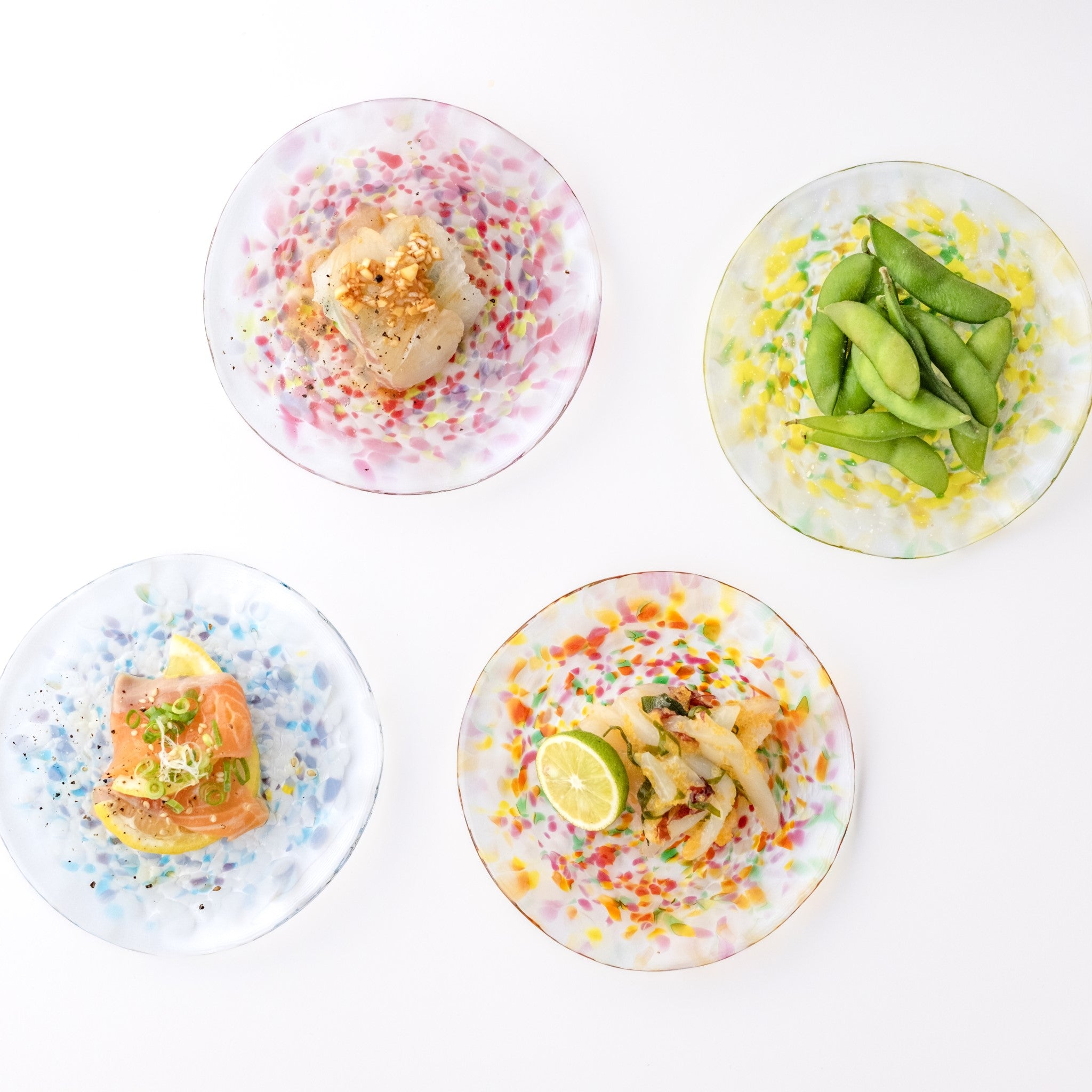 津軽びいどろ にほんの色 ふうけい 小皿 雪の灯 料理がよそわれたガラス皿がテーブルに並んでいる画像