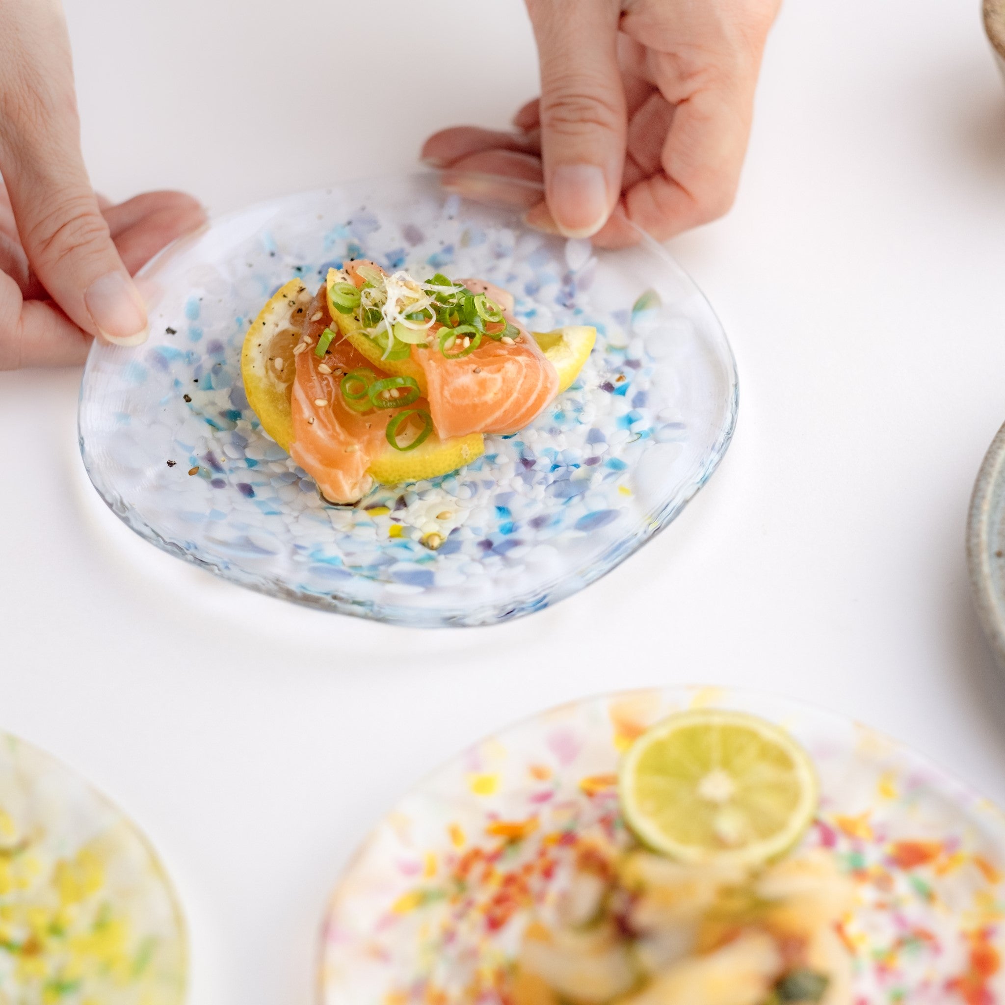 津軽びいどろ にほんの色 ふうけい 小皿 雪の灯 料理がよそわれたガラス皿がテーブルに並んでいる画像