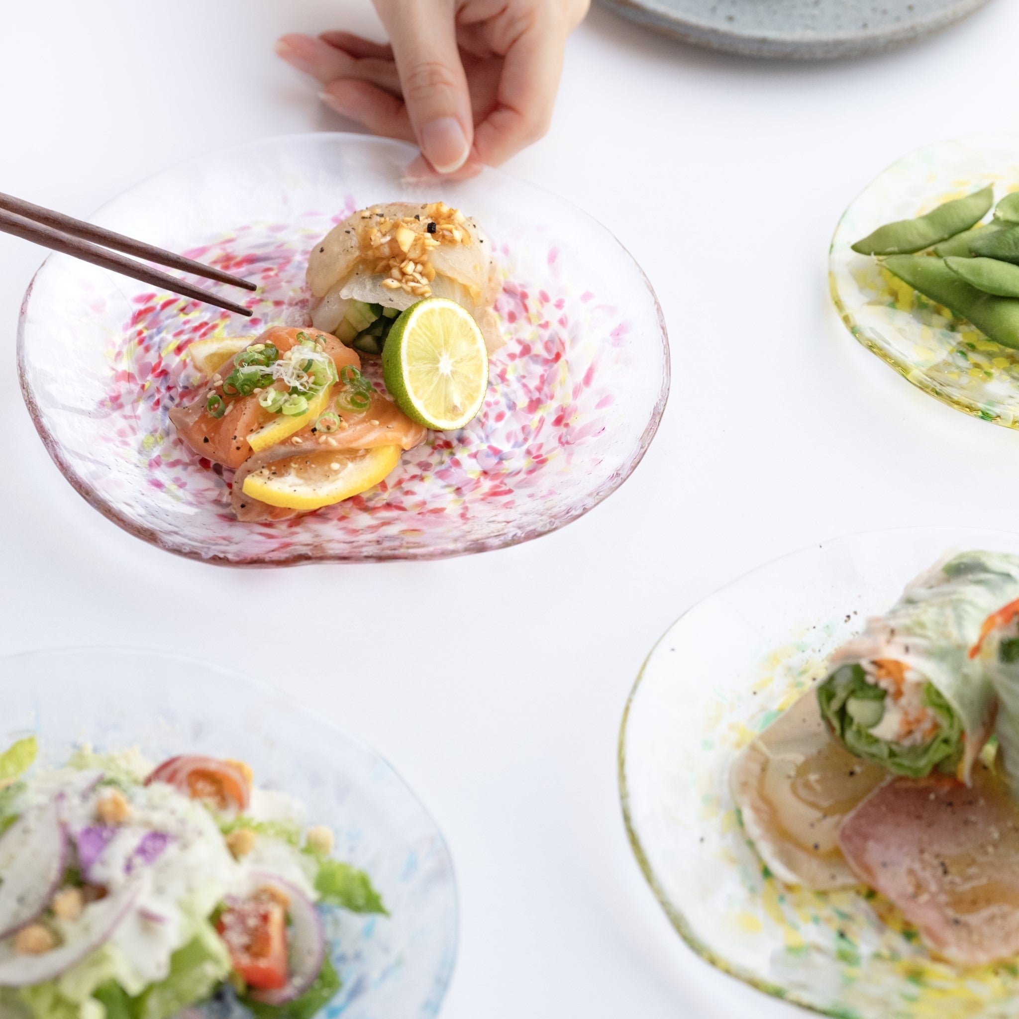 津軽びいどろ にほんの色 ふうけい 皿 舞う桜 料理がよそわれたガラス皿がテーブルに並んでいる画像