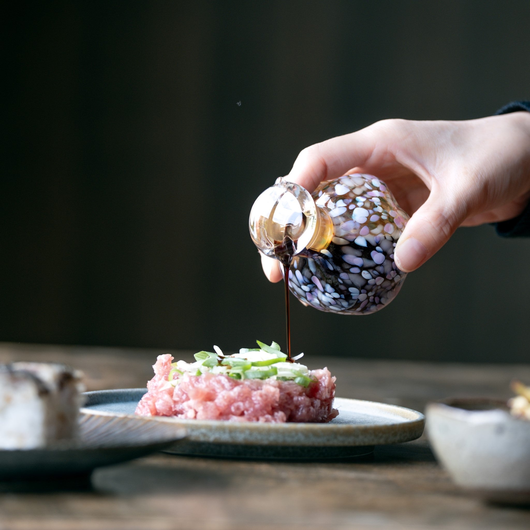 津軽びいどろ さくらさくら 桜と菜の花 醤油差し 醤油差しで海鮮にお醤油をかける画像
