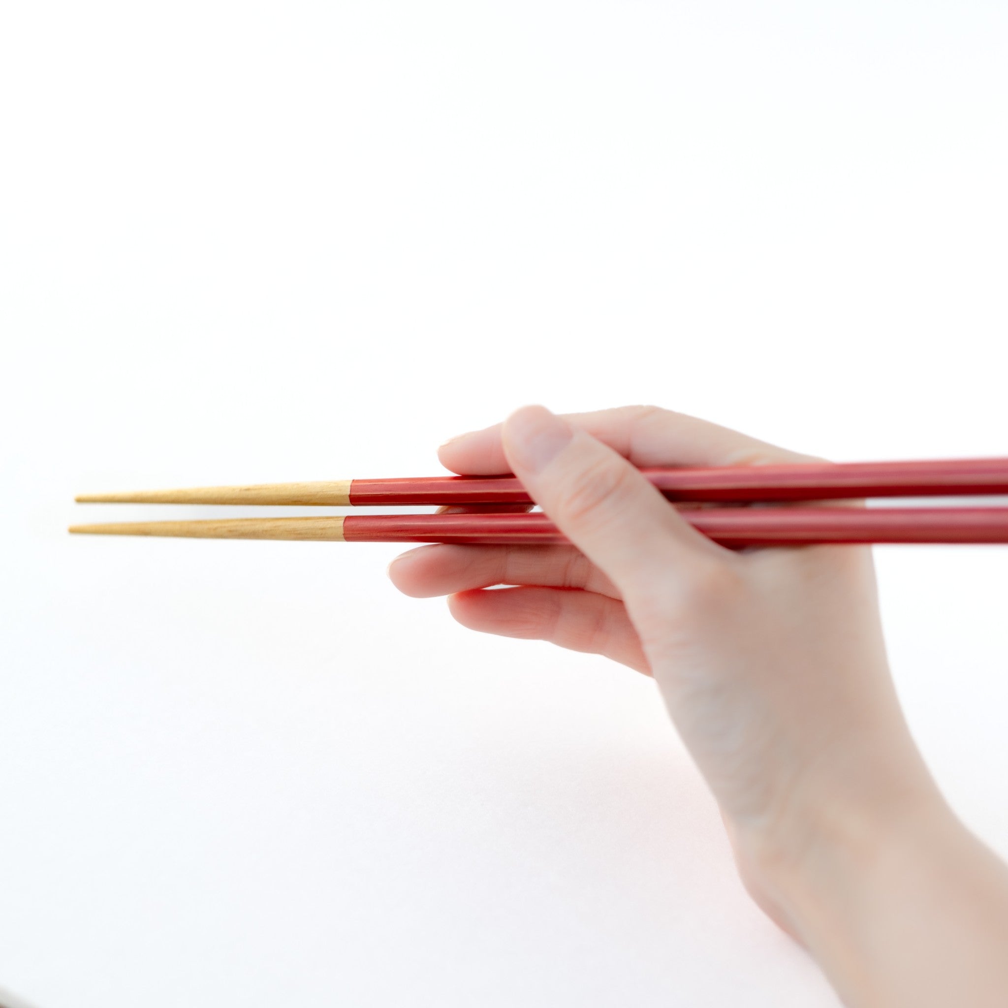 津軽びいどろ 津軽自然色りんご りんご箸置箸セット 若狭塗の箸を手で持っている画像