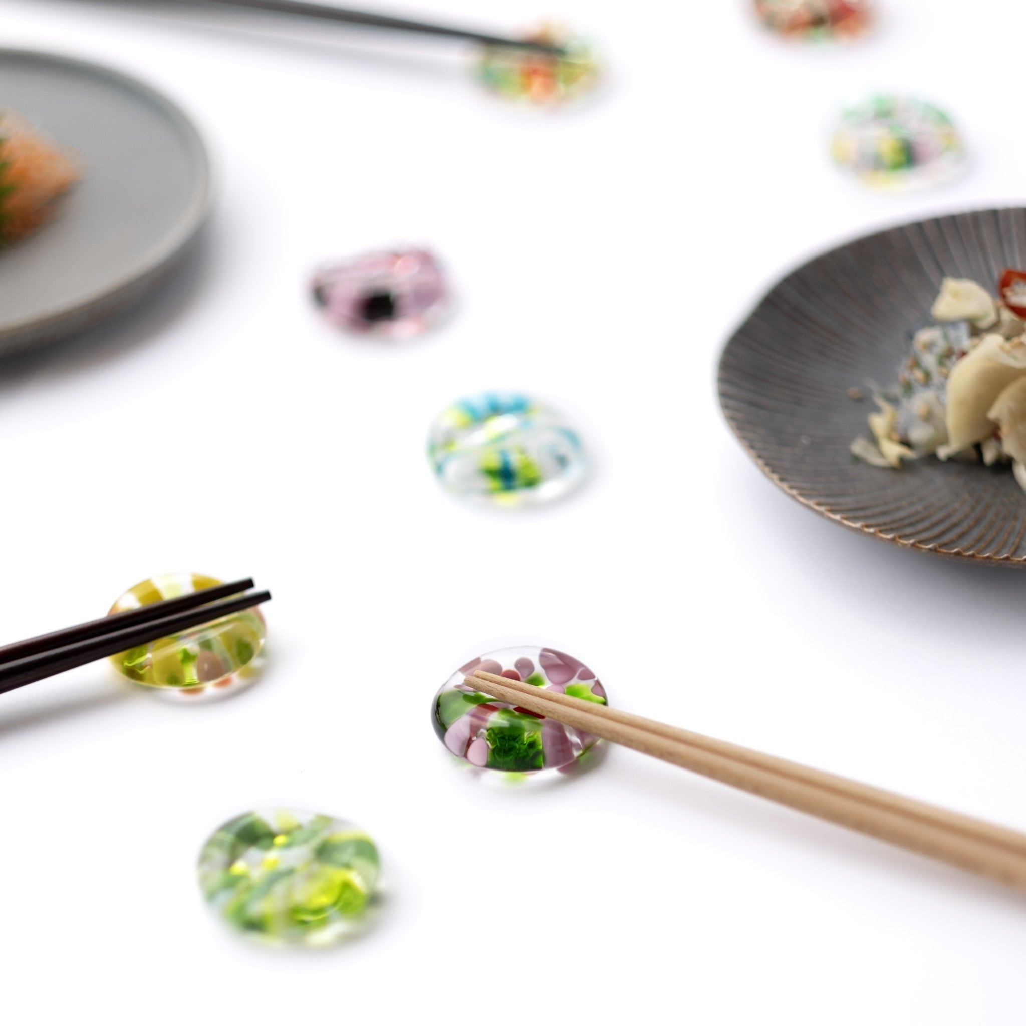 津軽びいどろ ⼗⼆花⽉ 箸置き 5月 スズラン カラフルな箸置きが食卓に並んでいる画像