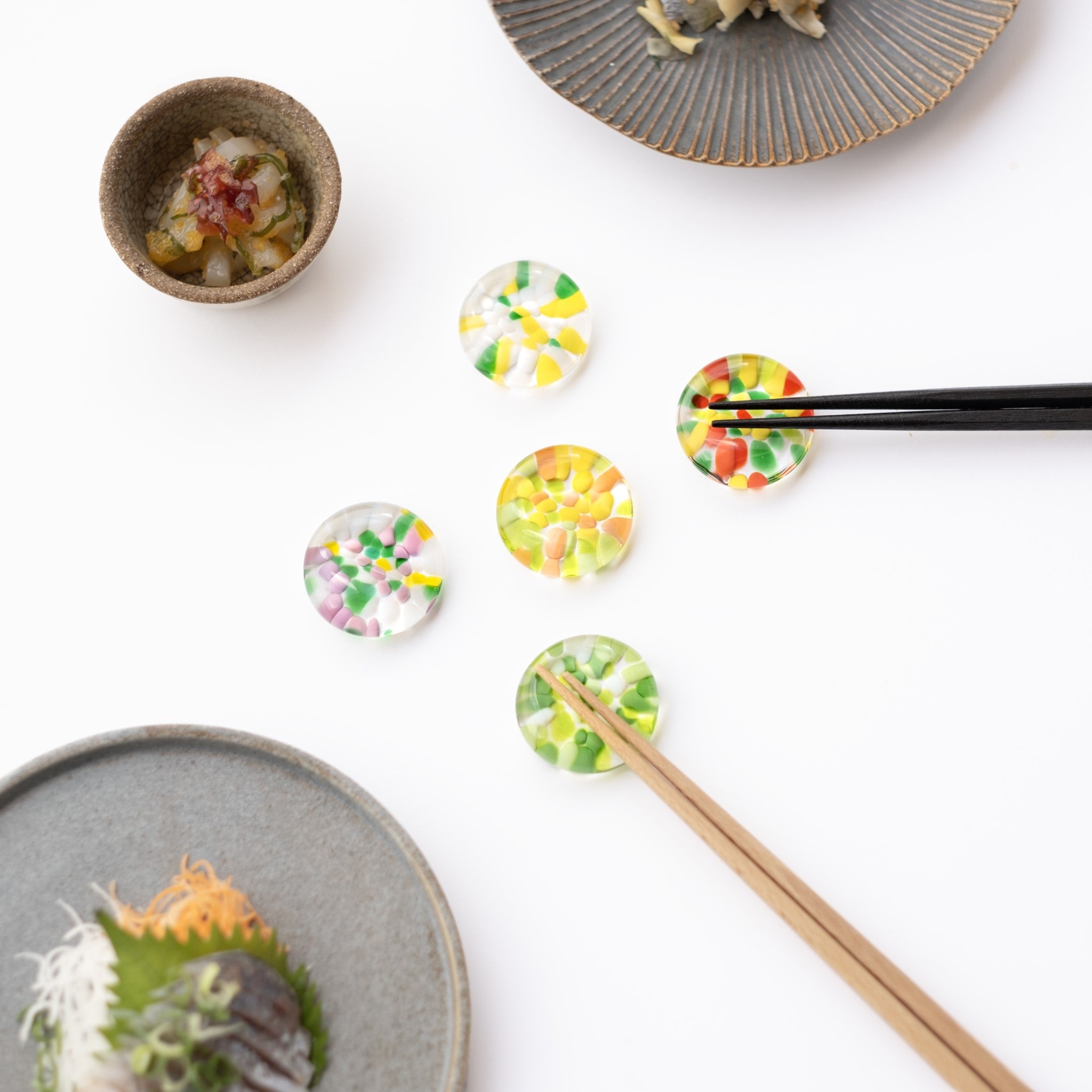 津軽びいどろ ⼗⼆花⽉ 箸置き 8月 ポピー カラフルな箸置きがテーブルに並んでいる画像