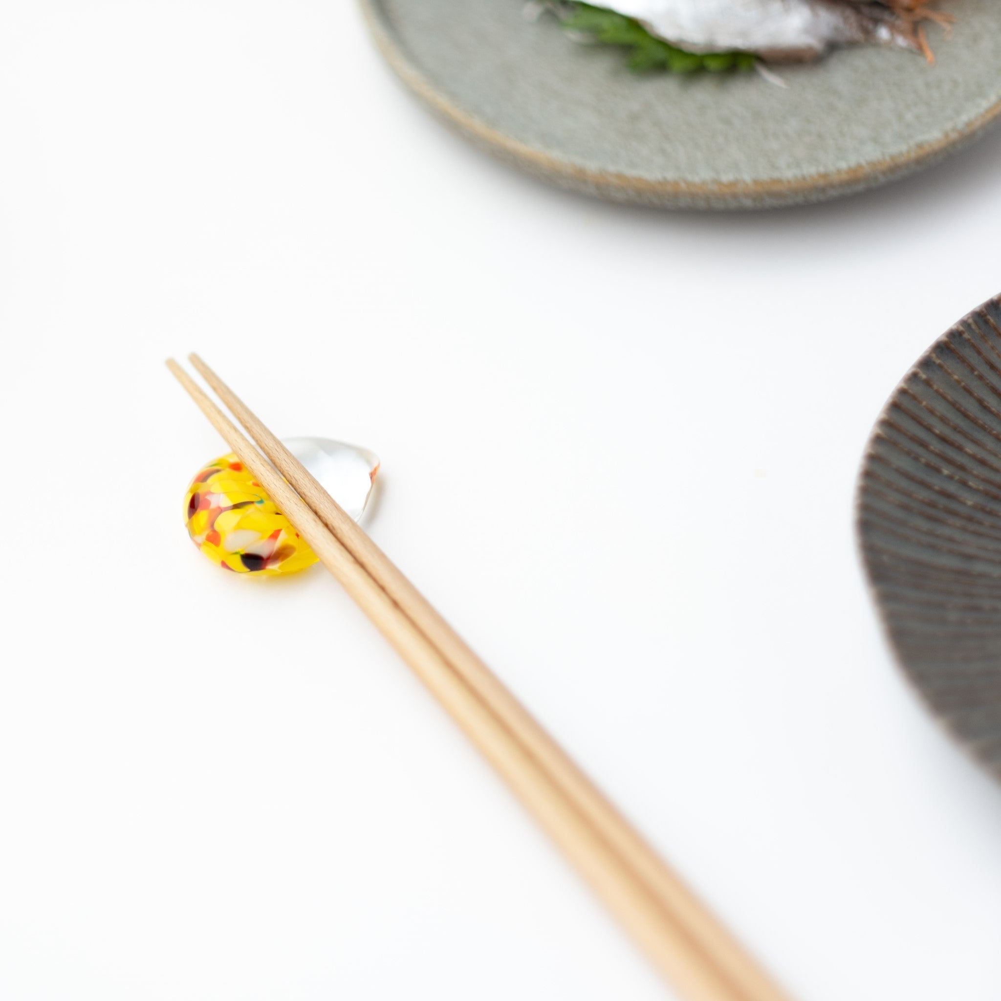 津軽びいどろ 白神の森響 箸置き ブナの⻩葉 黄色の箸置きに箸がセットされている画像