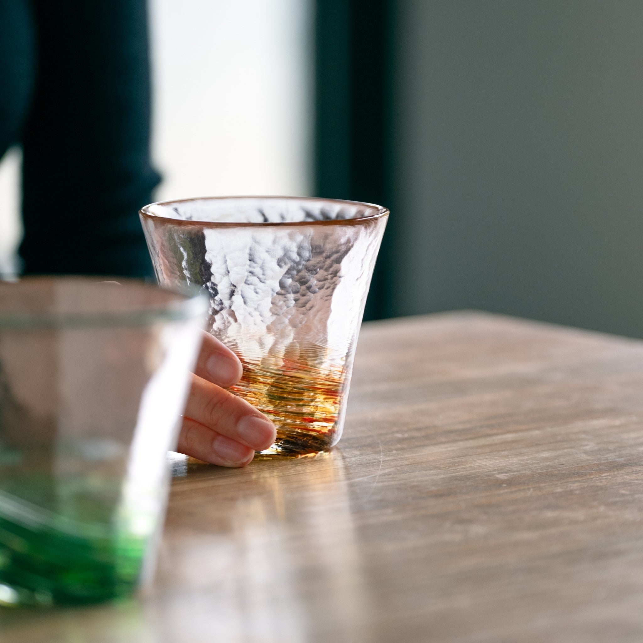 津軽びいどろ 六の色(むつのいろ) グラス 山 オレンジ色のグラスを手でつかんでいる画像