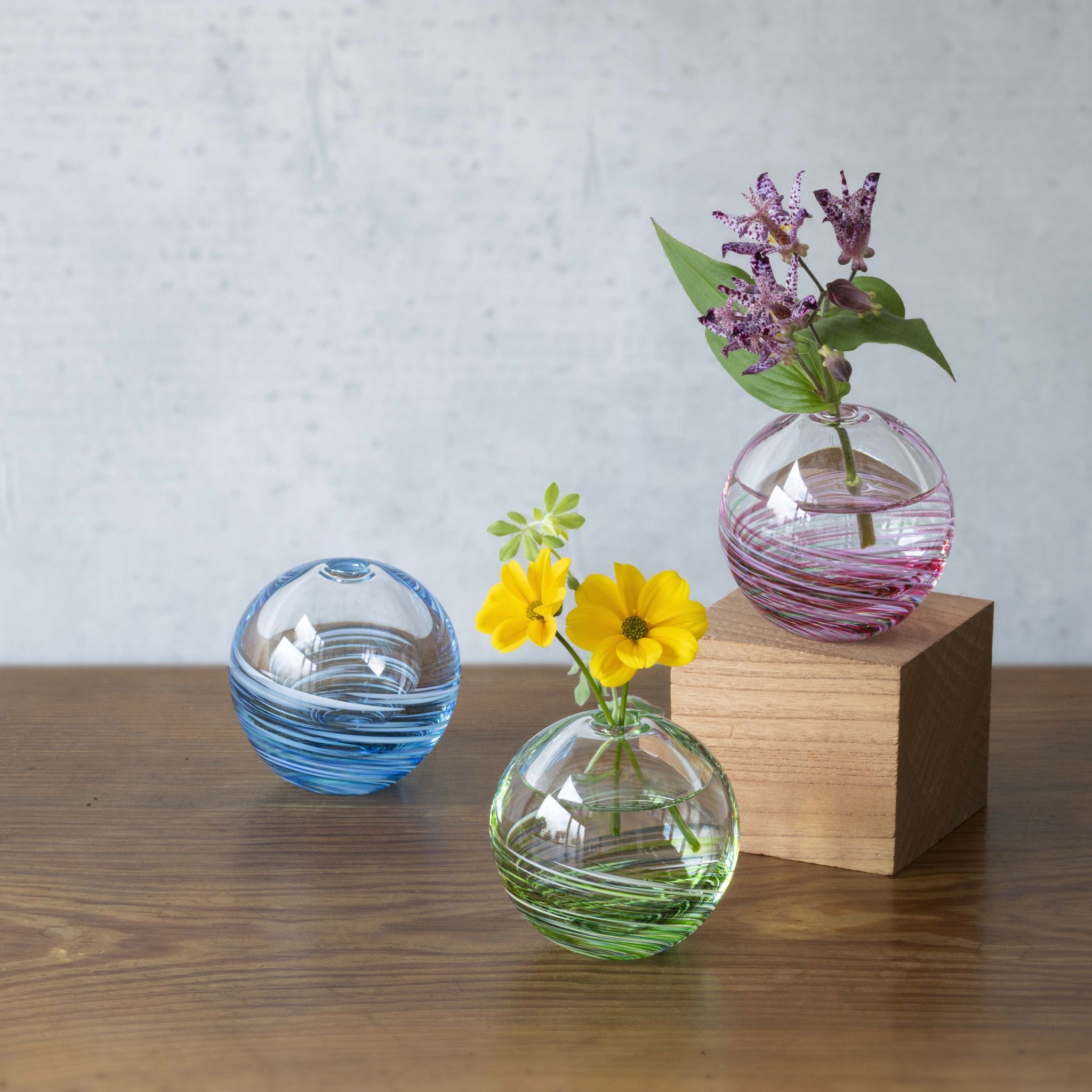 津軽びいどろ 六の色(むつのいろ) 一輪挿し 森 カラフルな花瓶がテーブルに並んでいる画像