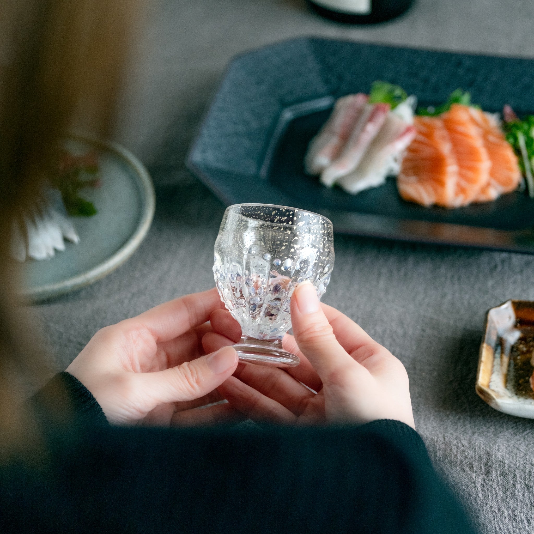 【販路限定】津軽びいどろ 雪うつし つぶ雪 盃 雪を表現したおちょこを両手で持っている画像