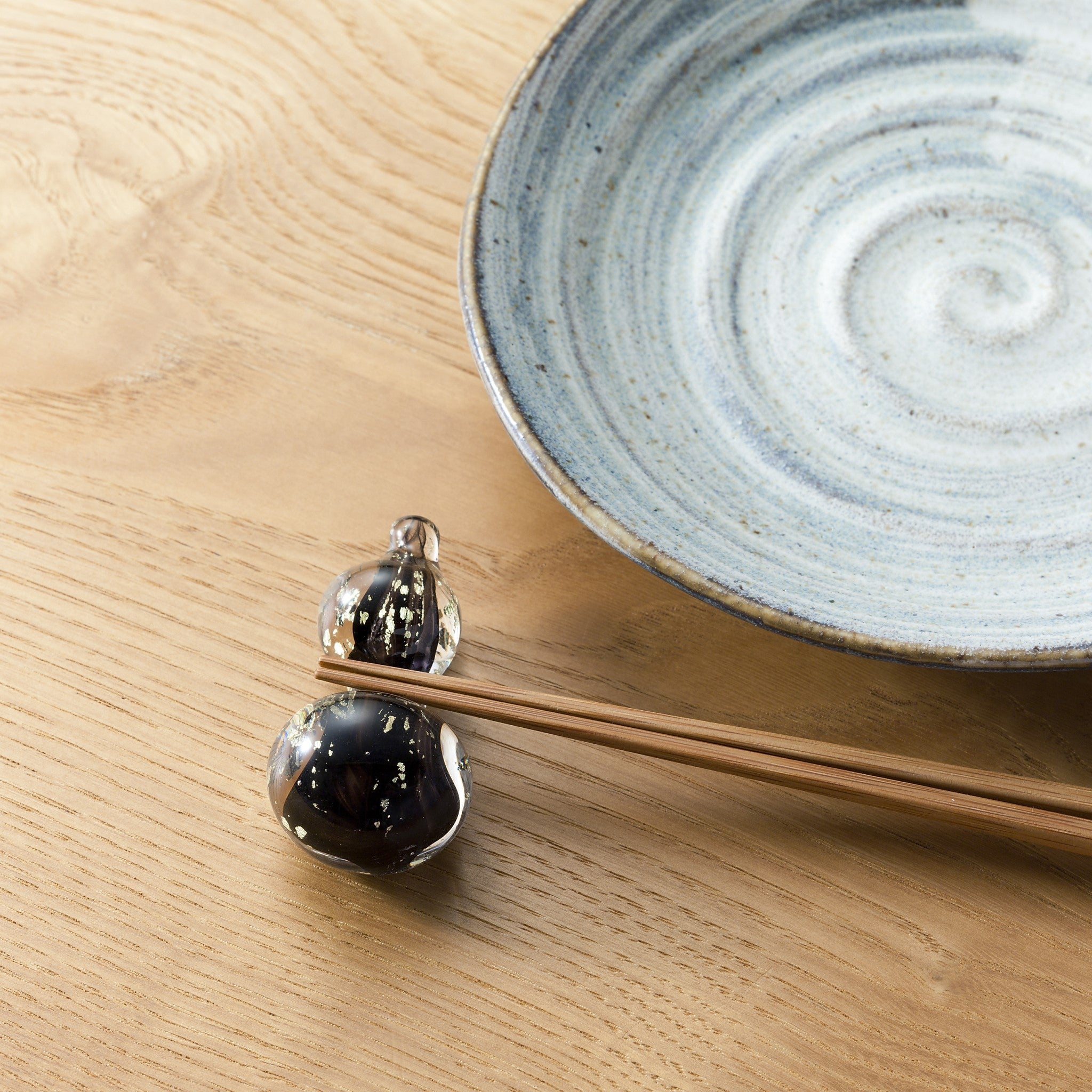 津軽びいどろ 箸置き ひょうたんブラック金 箸置きがテーブルに並んでいる画像