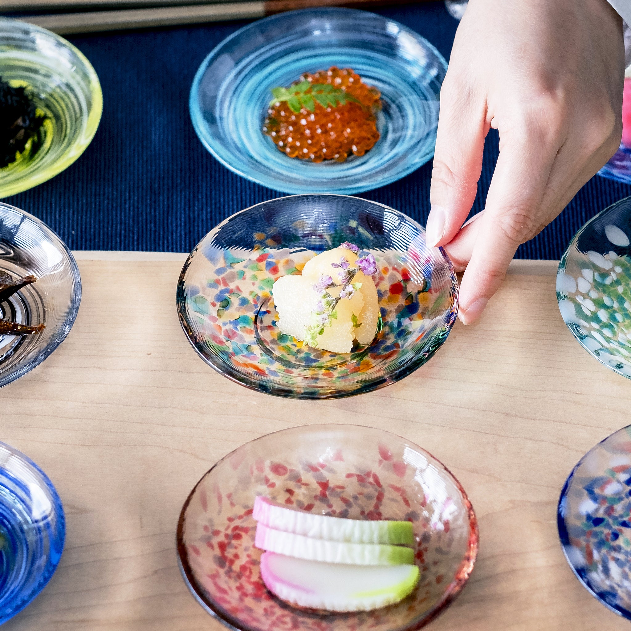 津軽びいどろ 色色豆皿 ねぶた夜祭 料理が乗った小皿を手で持ち上げている画像