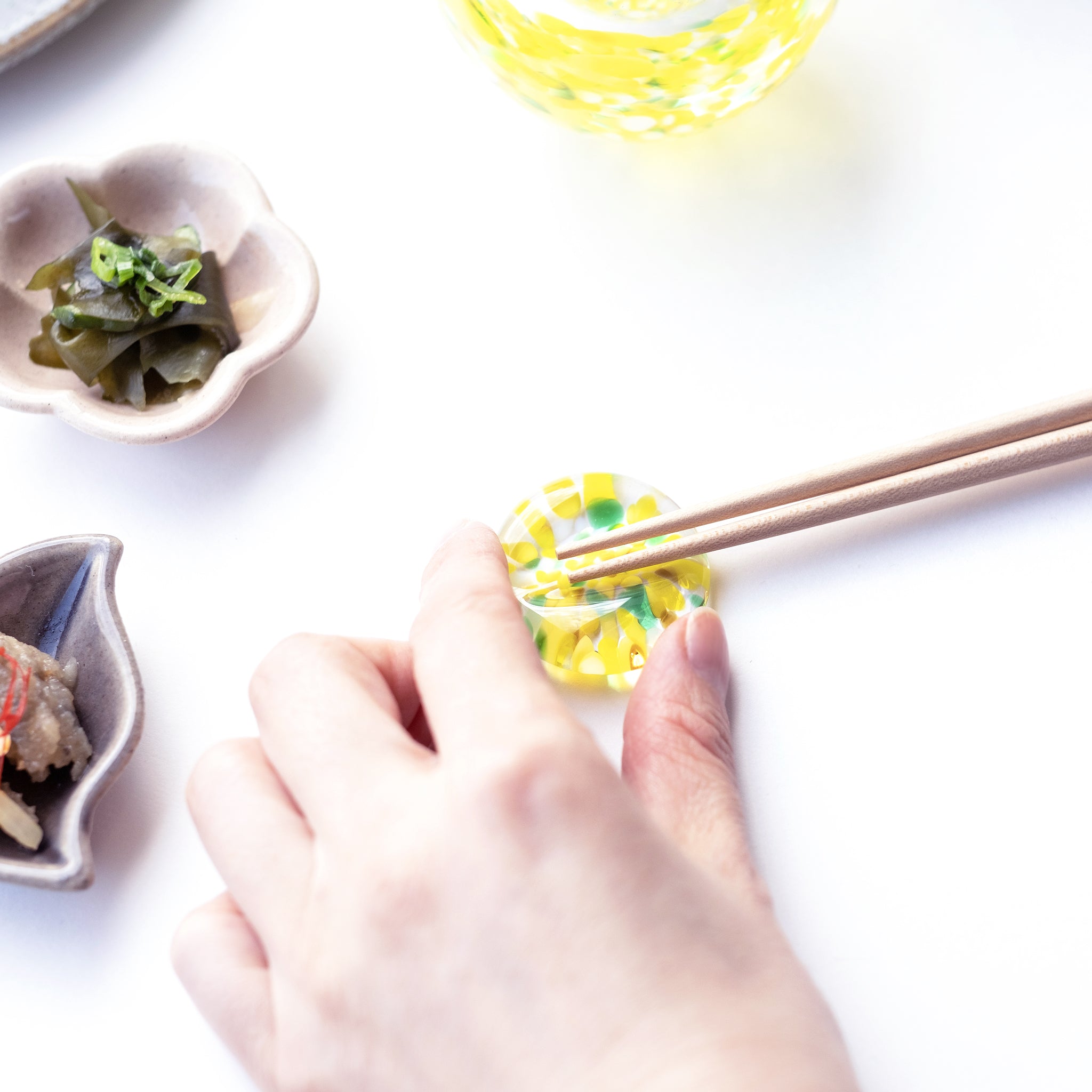 津軽びいどろ にほんの色ふうけい 箸置き 向日葵 箸と箸置きを手でつかんでいる画像