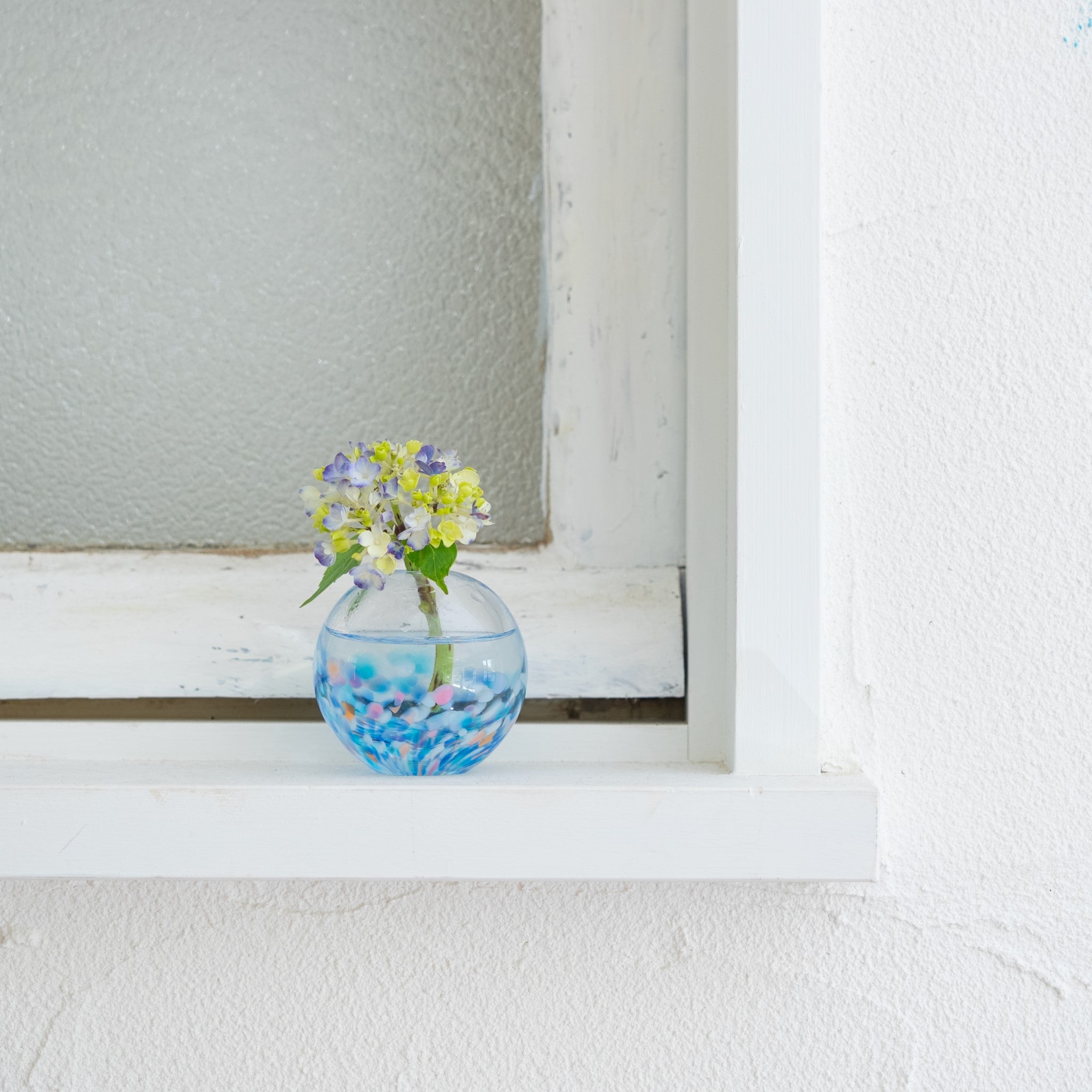 津軽びいどろ にほんの色 ふうけい 一輪挿し 夕凪の空 窓際に置かれた丸い花瓶の画像
