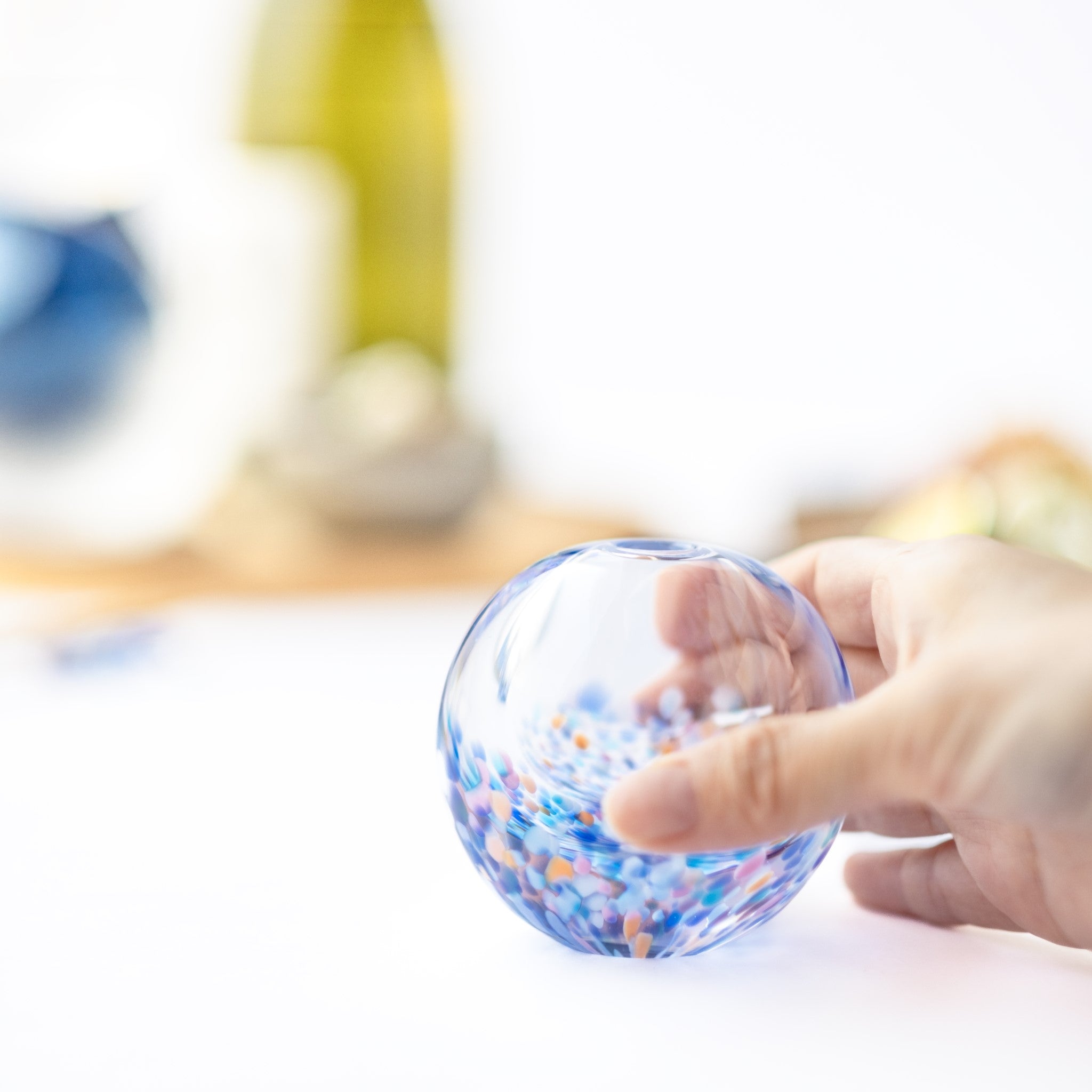 津軽びいどろ にほんの色 ふうけい 一輪挿し 夕凪の空 丸い花瓶を手でつかんでいる画像