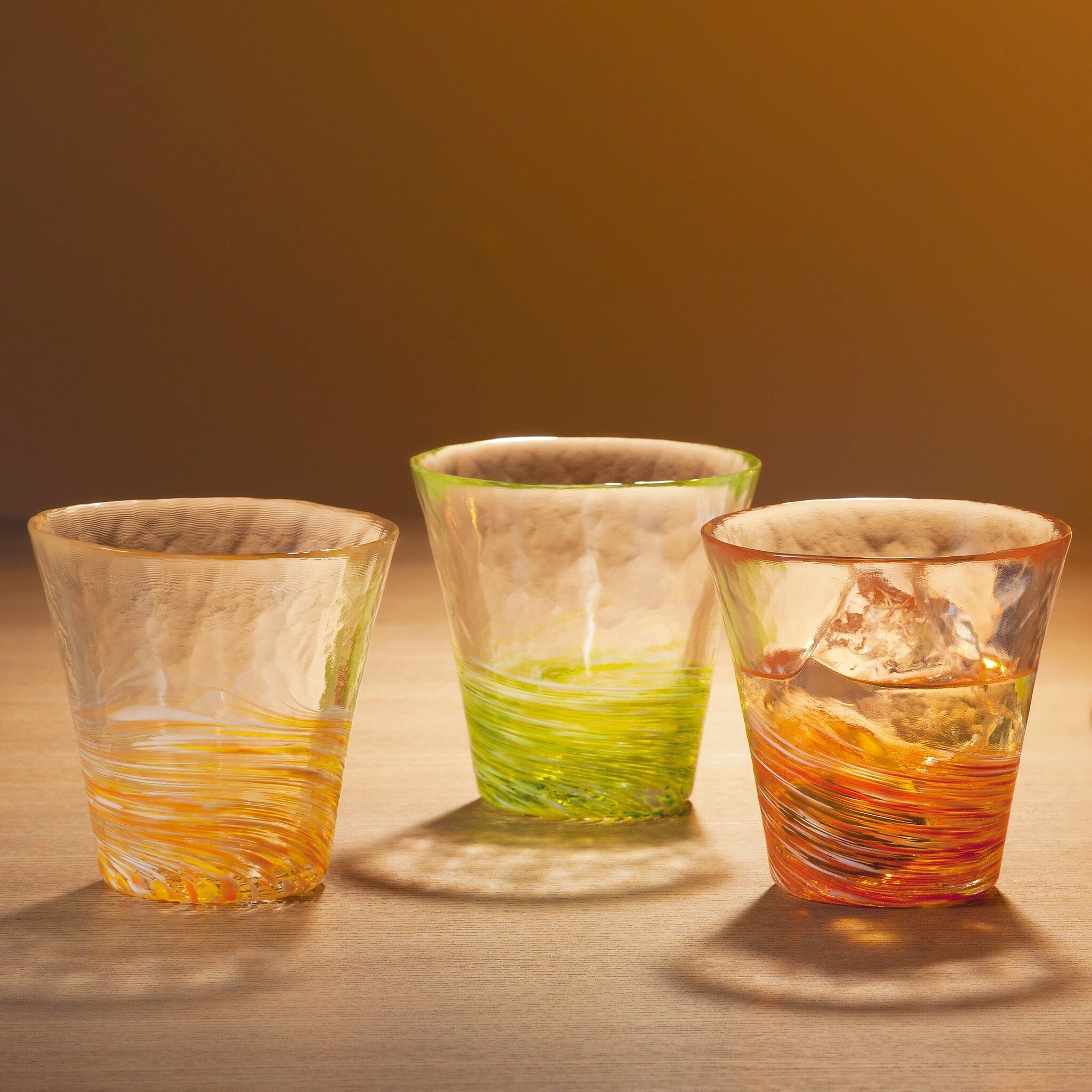 津軽びいどろ 12色のグラス 山吹 色違いのグラスがテーブルに並んでいる画像