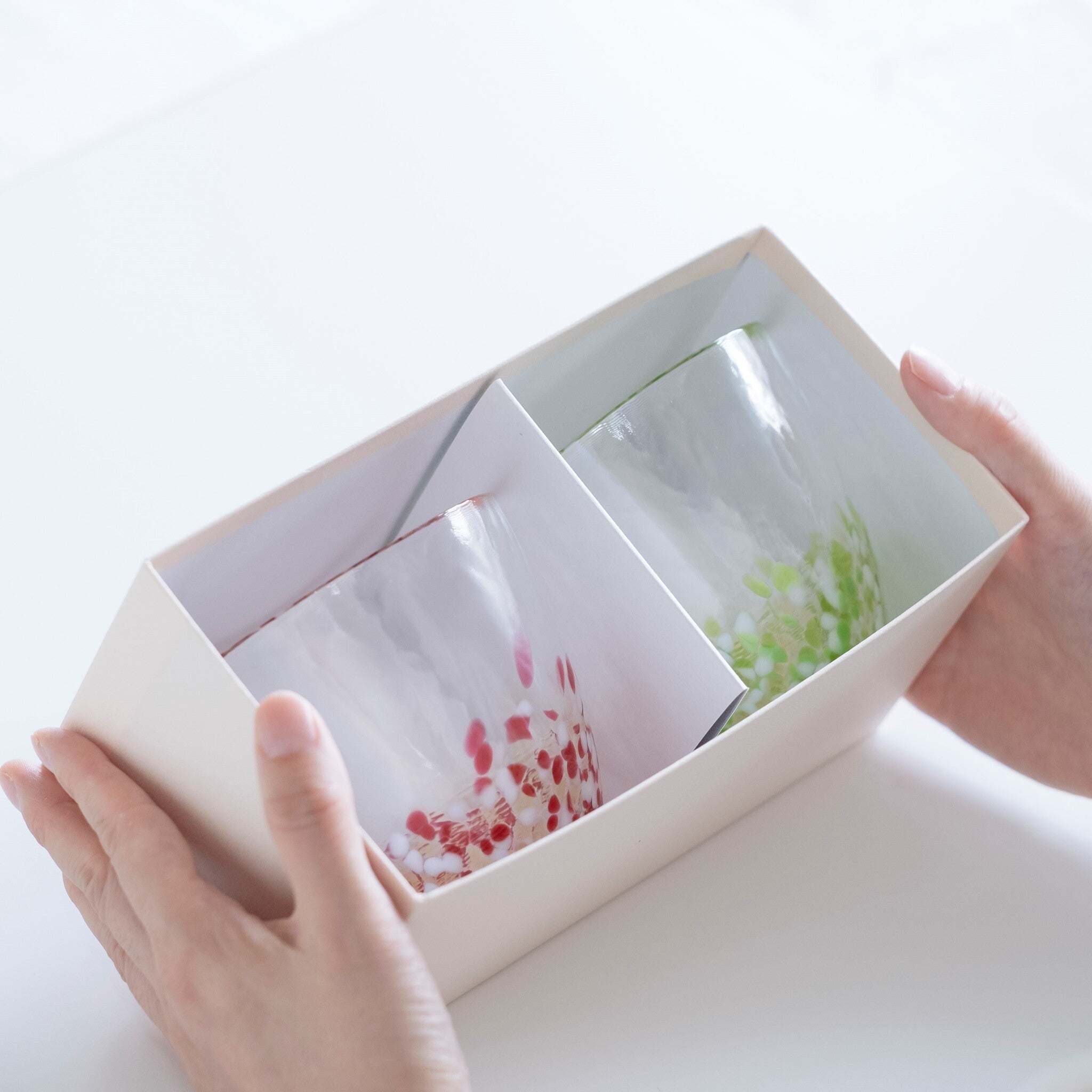 津軽びいどろ りんご カップペア グラスが入った化粧箱を手で持っている画像