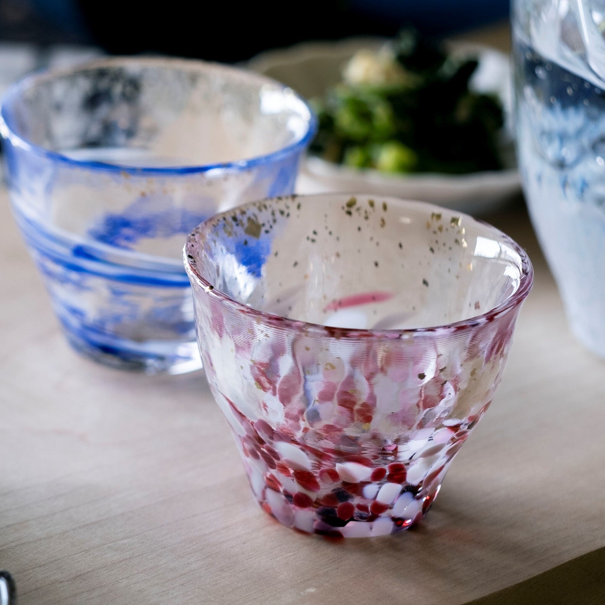 津軽びいどろ 金彩ぐいのみ こぼれ桜 柄違いの盃がテーブルに並んでいる画像