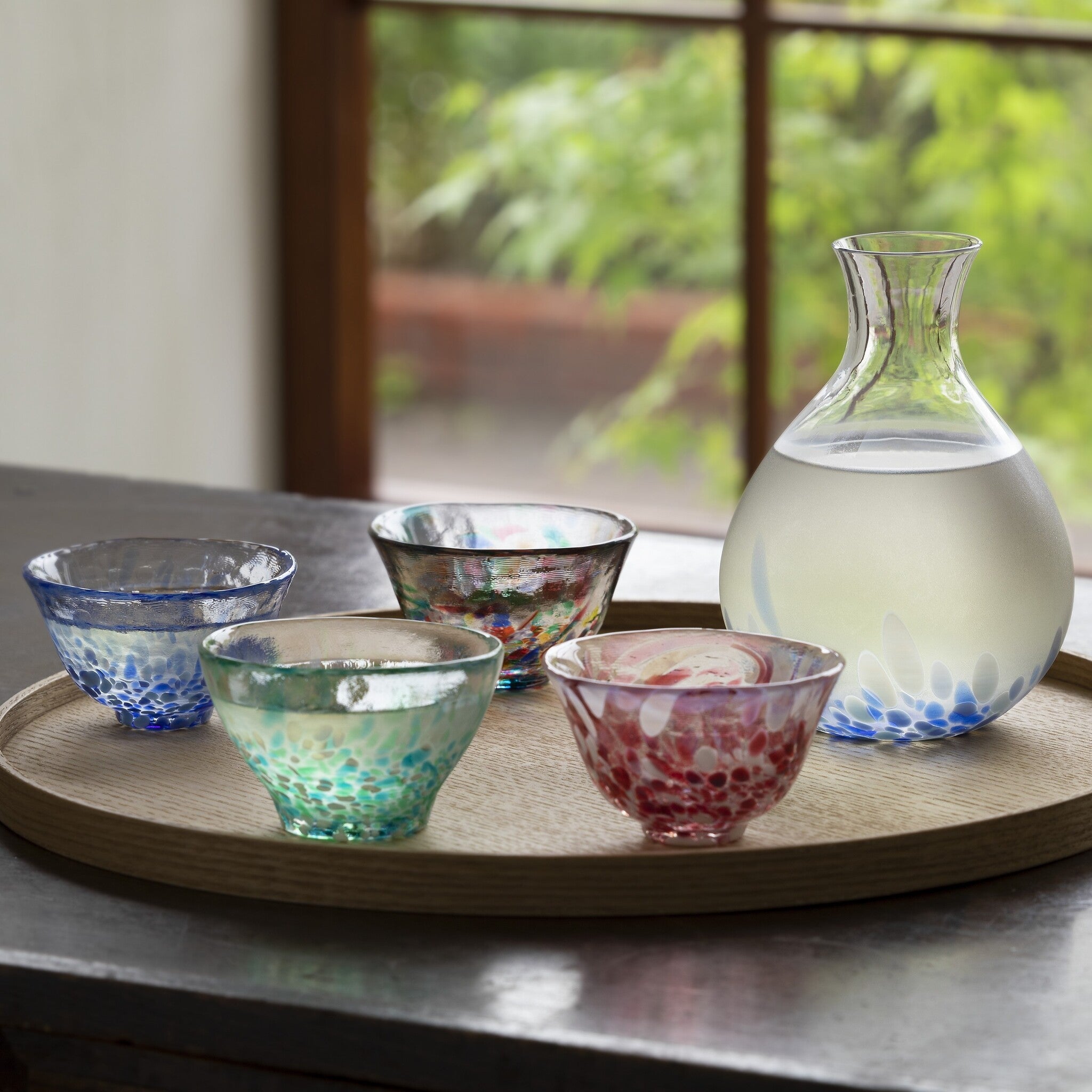 津軽びいどろ 徳利 岩清水 色違いの盃と日本酒の入った徳利がお盆に並んでいる画像