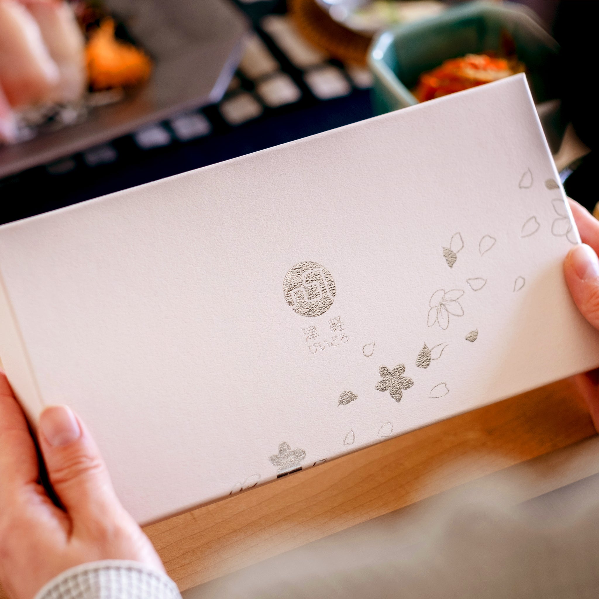 津軽びいどろ 豆皿ギフト SAKURAペアセット菜の花と青い空 化粧箱を手で持ち上げている画像