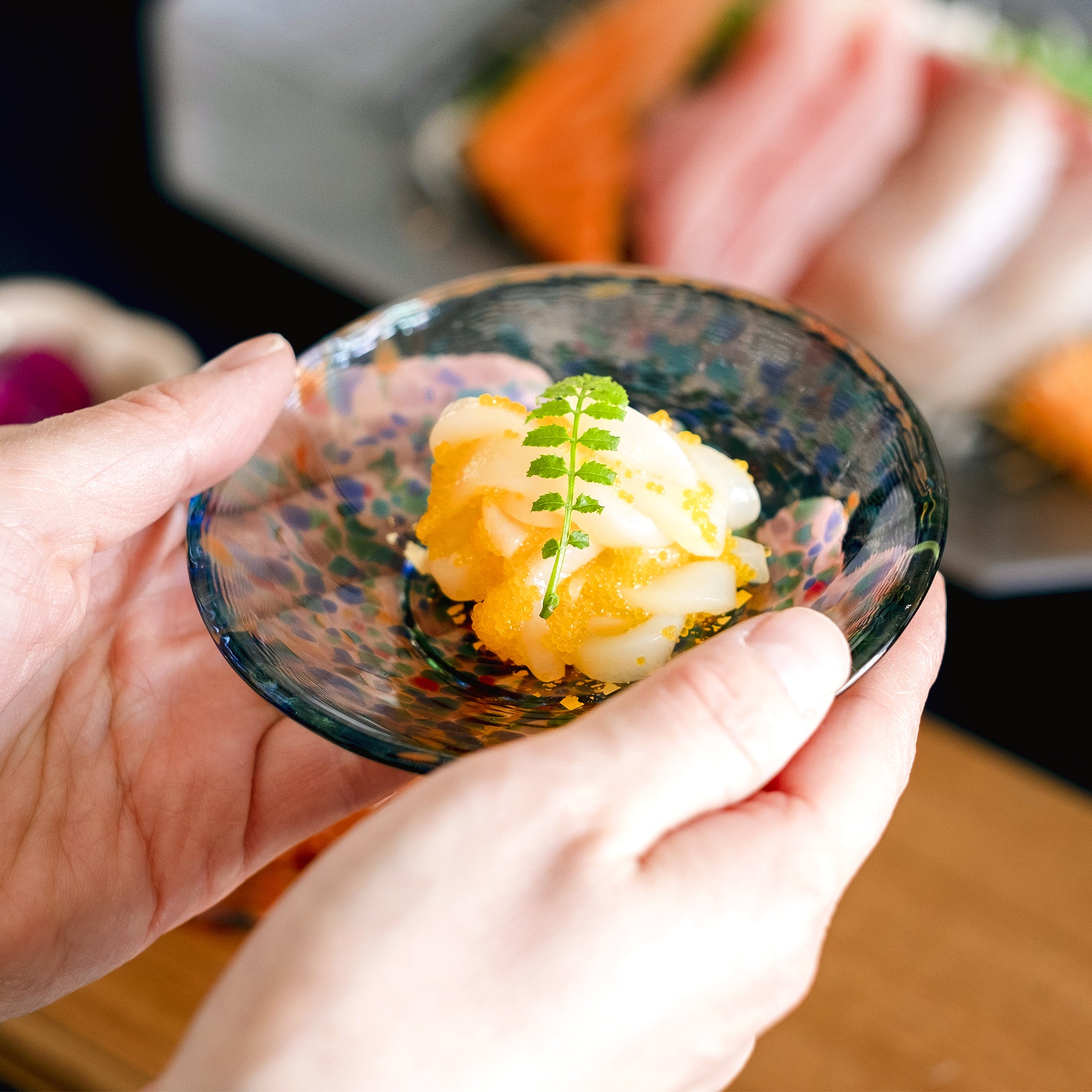 津軽びいどろ 豆皿ギフト MATSURI金彩ペアセット 料理がよそわれたガラス食器を手で持ち上げている画像