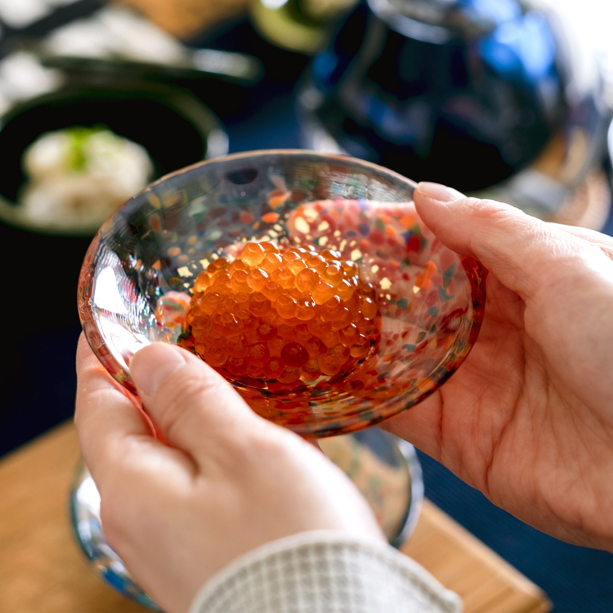 津軽びいどろ 豆皿ギフト MATSURI金彩ペアセット いくらがよそわれたガラス食器を手で持ち上げている画像