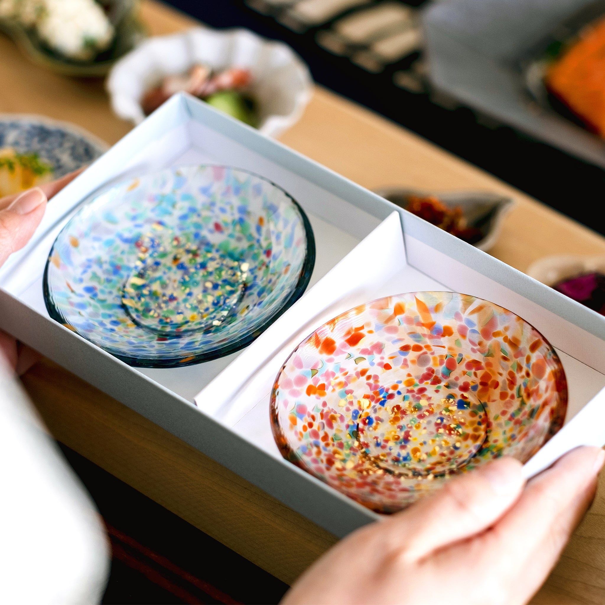 津軽びいどろ 豆皿ギフト MATSURI金彩ペアセット ガラス食器が入った化粧箱を手で持ち上げている画像