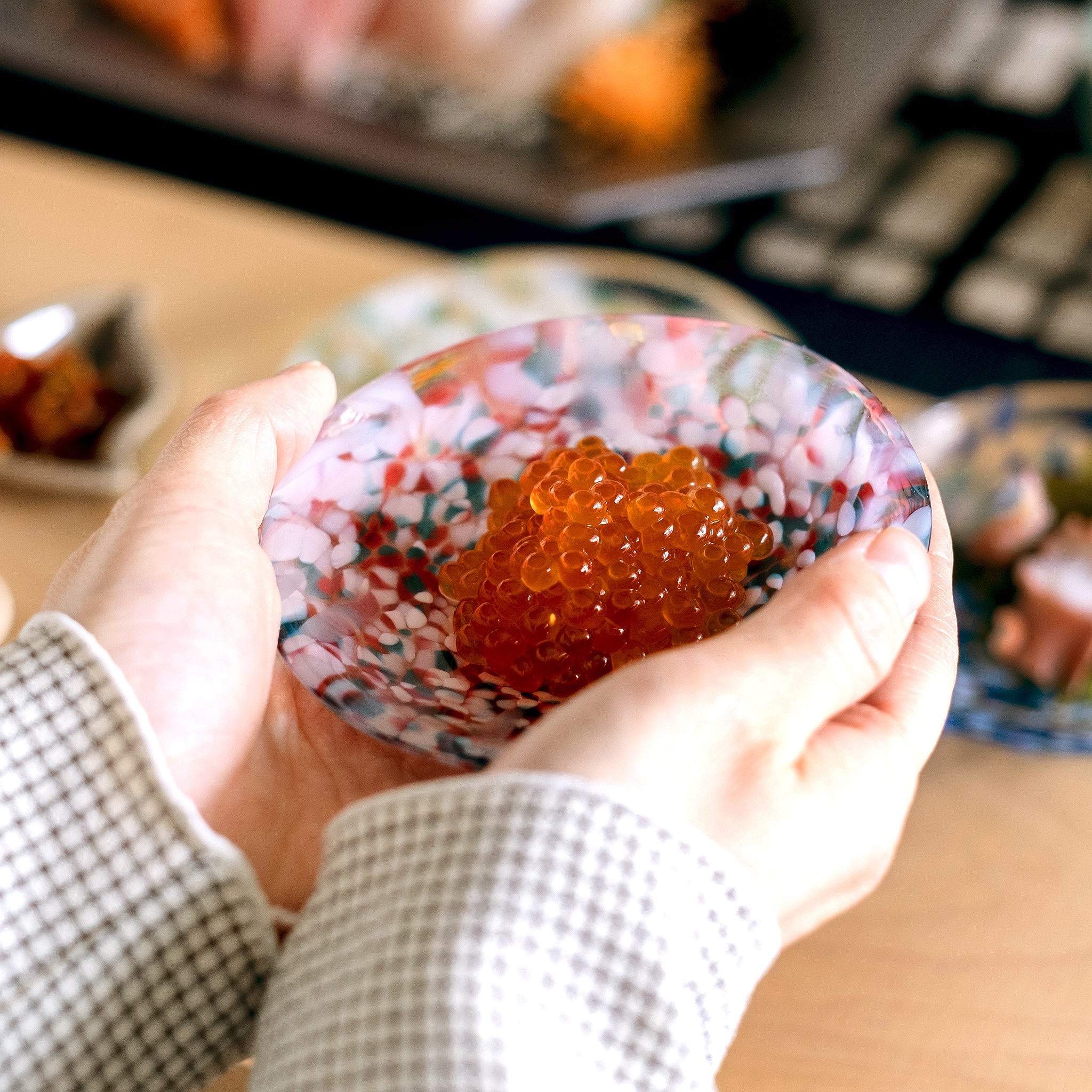 津軽びいどろ 豆皿ギフト 色色豆皿彩合わせセット いくらがよそわれたガラス食器を手で持ち上げている画像