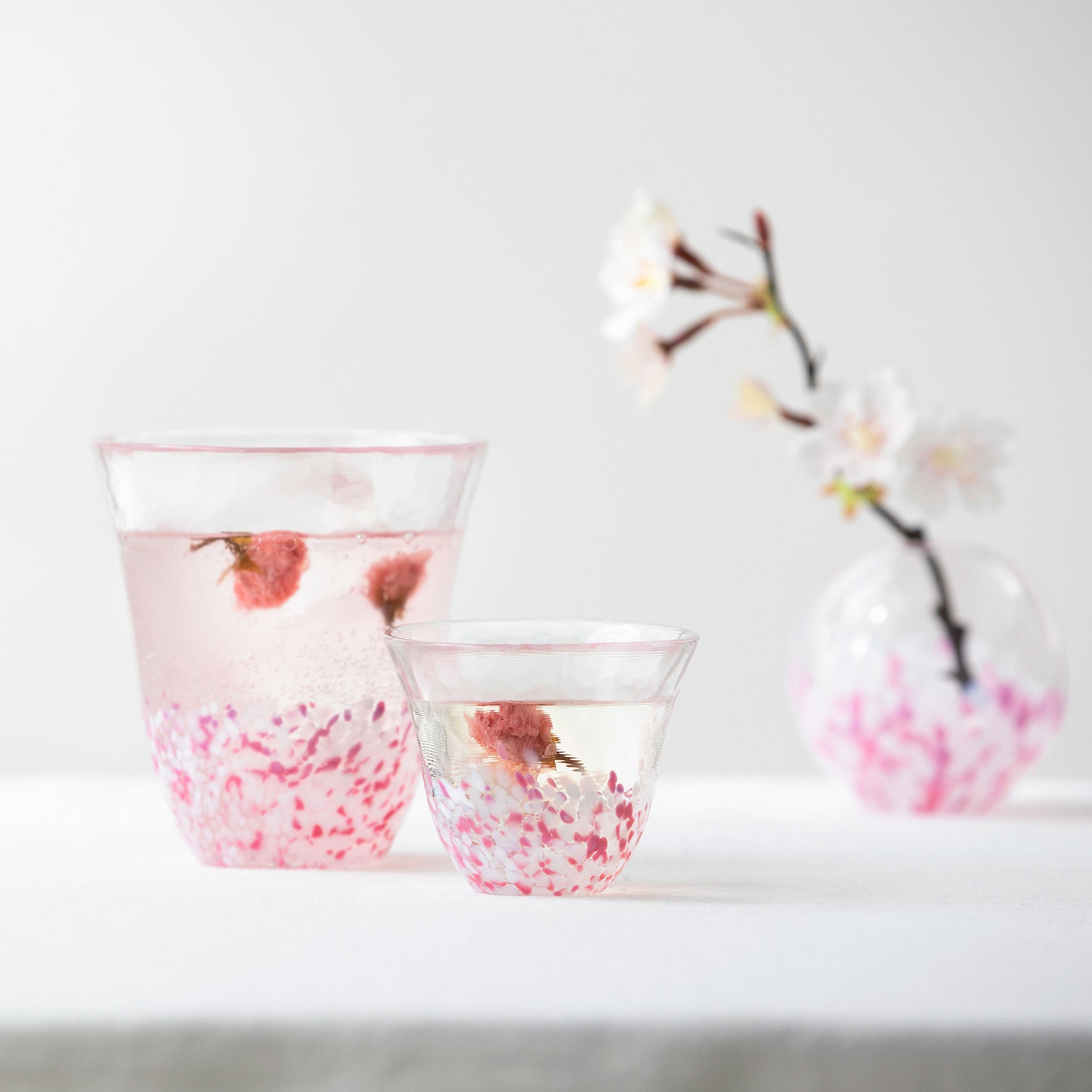 津軽びいどろ さくらさくら sakura一輪挿し グラスと盃と並んでいる花瓶の画像