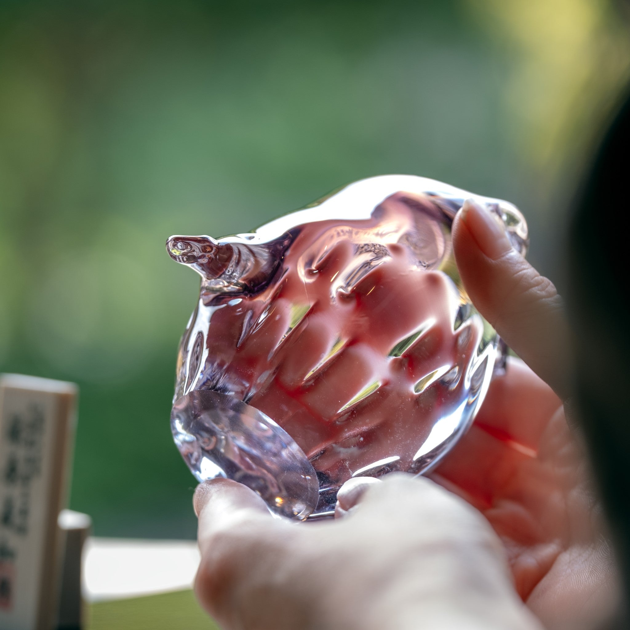 津軽びいどろ 子ふくろう (紫暮) 紫色のふくろうのガラス置物を手で持っている画像