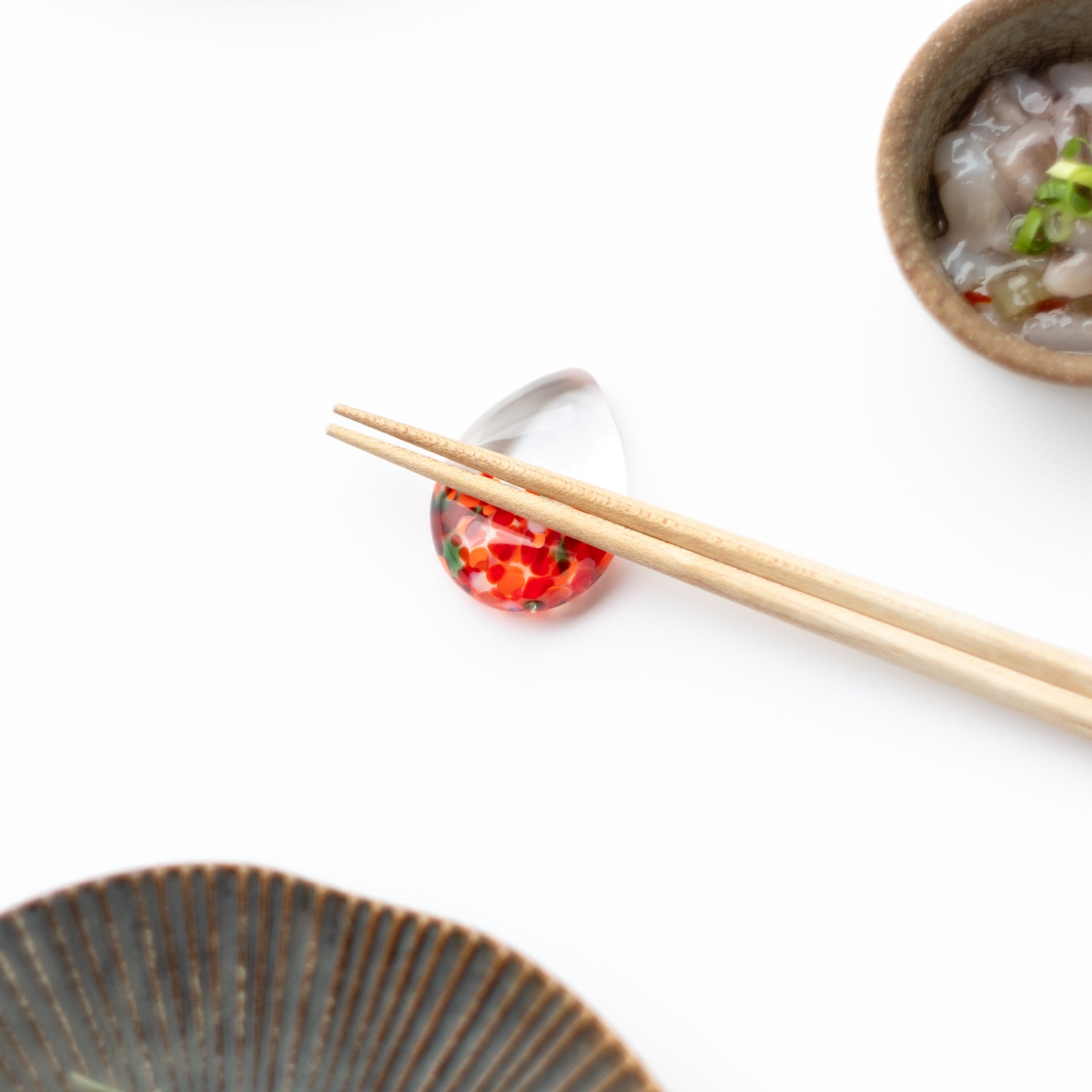 津軽びいどろ 白神の森響 箸置き アカショウビン 箸がセットされた赤色の箸置きの画像