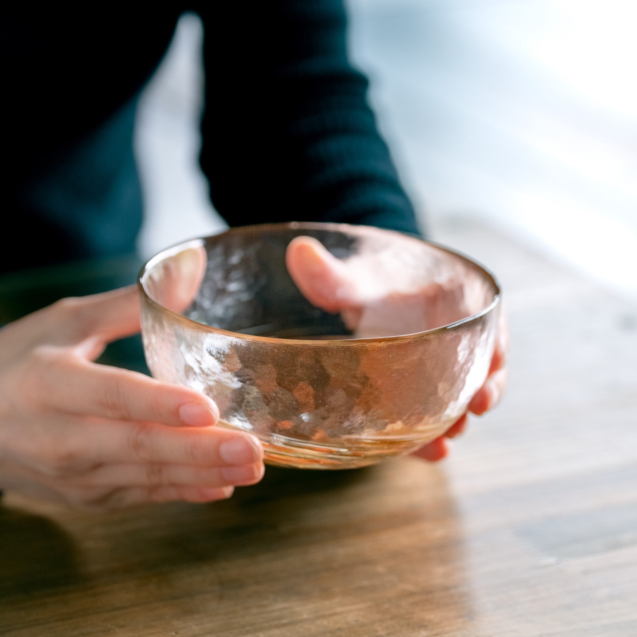 津軽びいどろ 六の色(むつのいろ) 小鉢 山 オレンジ色のガラス小鉢を両手で持ち上げた画像