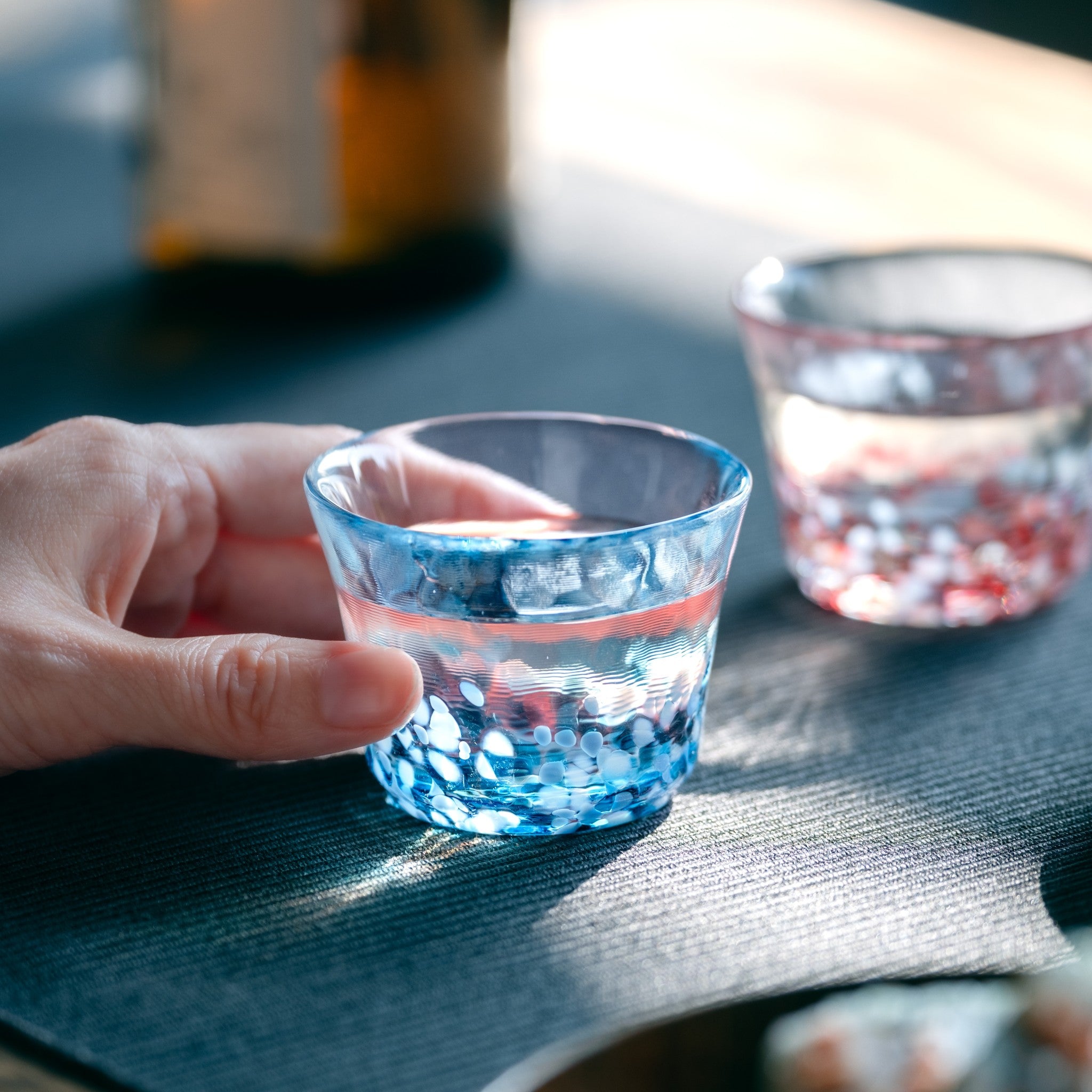 津軽びいどろ 盃コレクション 盃青涼 色違いの盃がテーブルに並んでいる画像