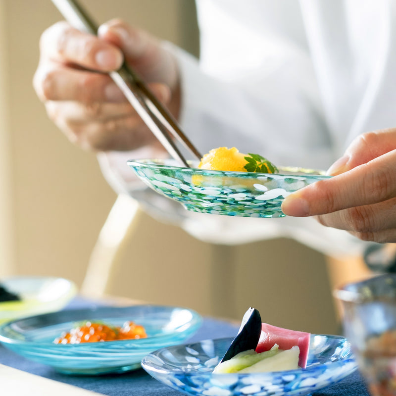 津軽びいどろ 色色豆皿 みずばしょう 料理が乗った小皿を手で持ち上げている画像