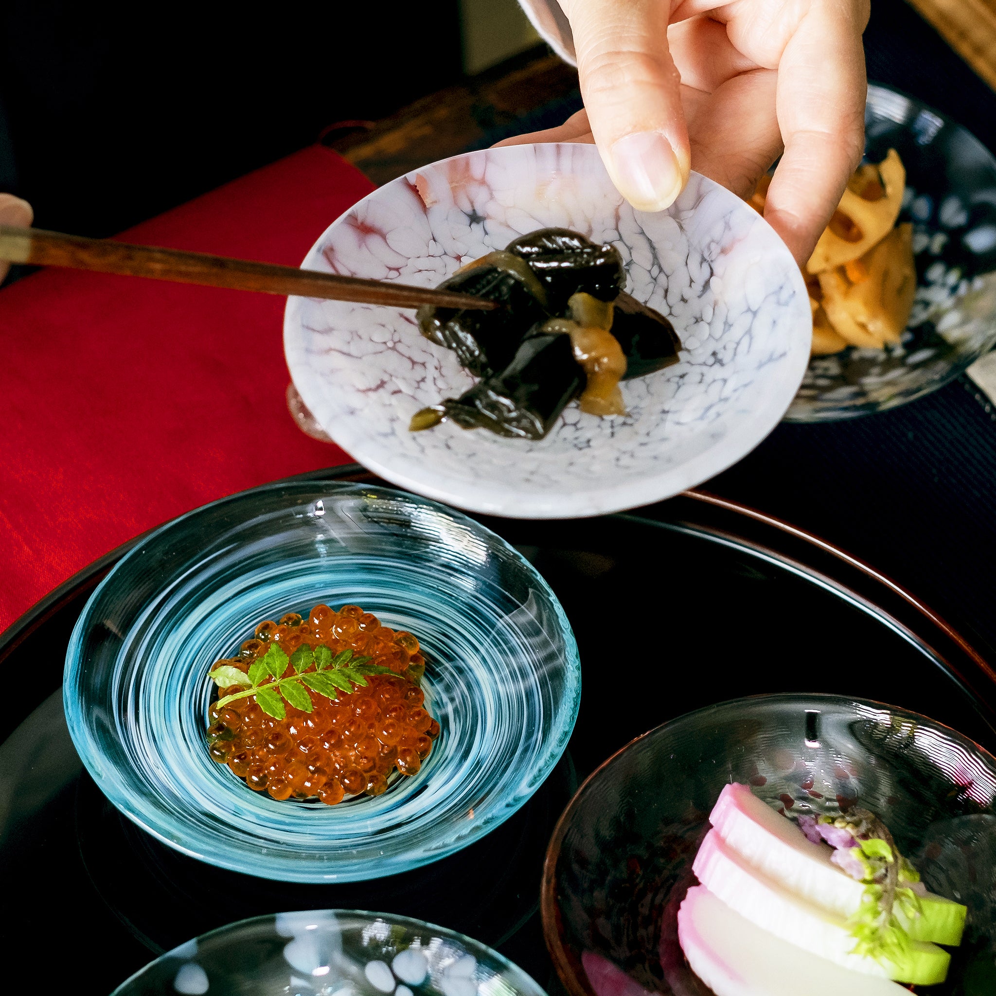  津軽びいどろ 色色豆皿 淡雪 料理が乗った小皿を手で持ち上げている画像