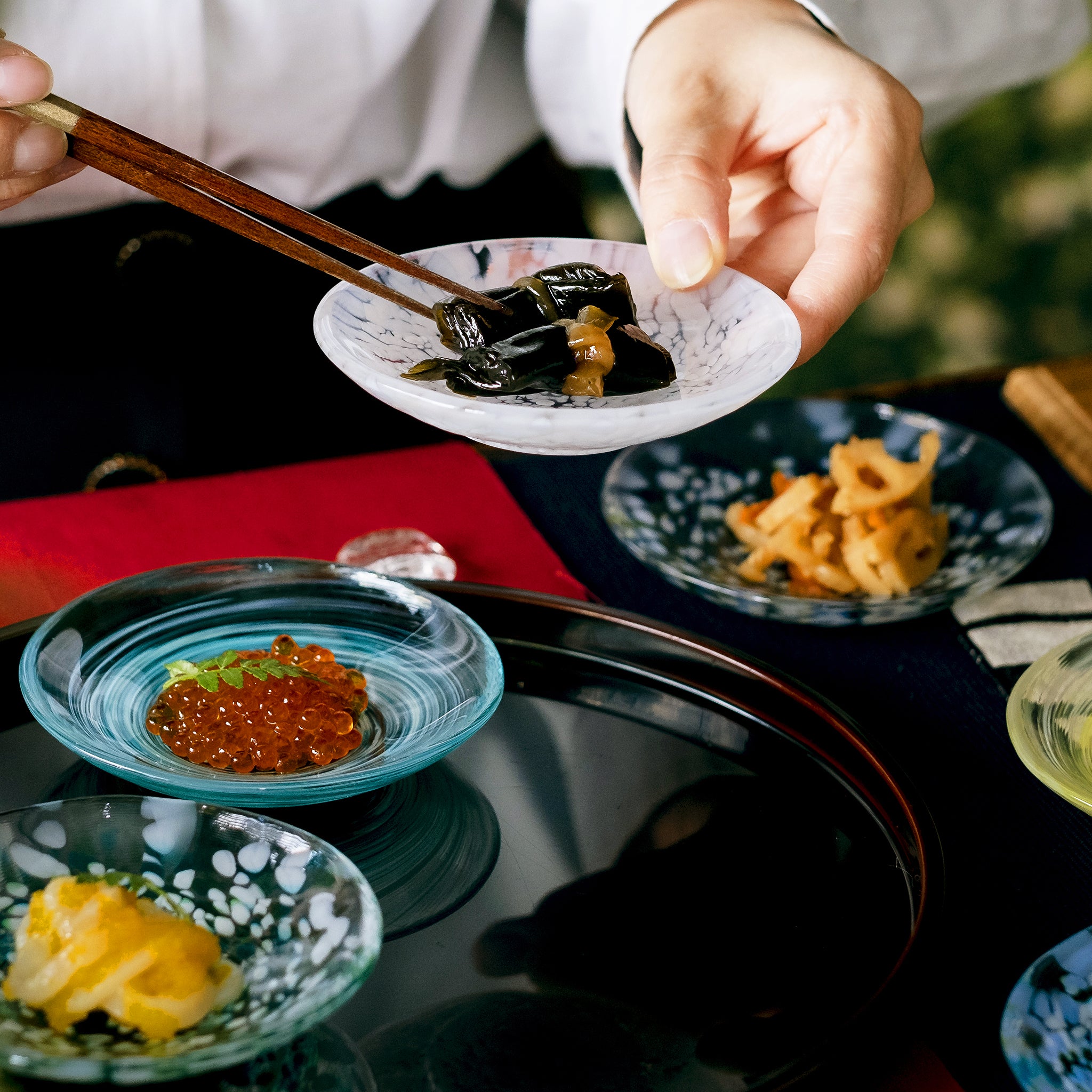 津軽びいどろ 色色豆皿 淡雪 料理が乗った小皿を手で持ち上げている画像