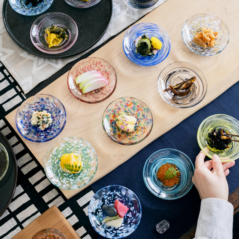 津軽びいどろ 色色豆皿 紺青 料理が乗った色違いの小皿がテーブルに並んでいる画像
