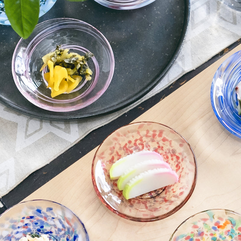 津軽びいどろ 色色豆皿 花風 料理が乗った色違いの小皿が食卓に並んでいる画像