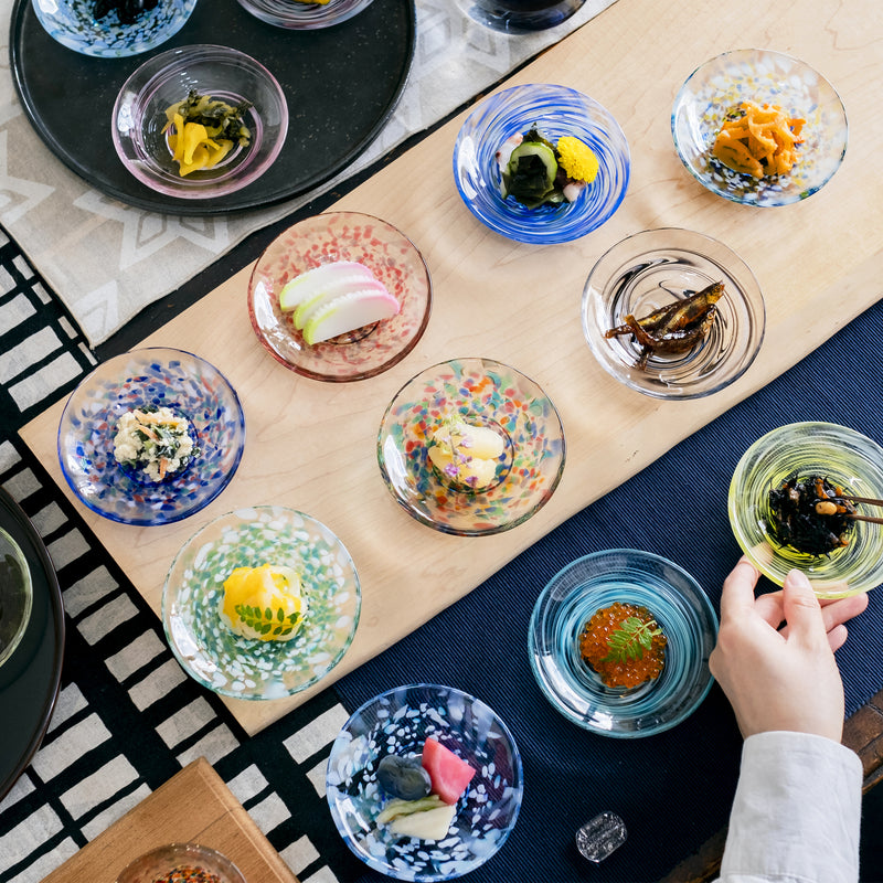 津軽びいどろ 色色豆皿 しずく 料理が乗った小皿がテーブルにたくさん並んでいる画像