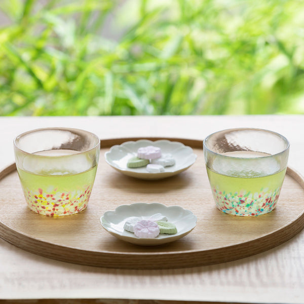  津軽びいどろ さくらさくら sakuraフリーグラスペア菜の花と青い空 茶菓子とお茶が入ったグラスが並んでいる画像