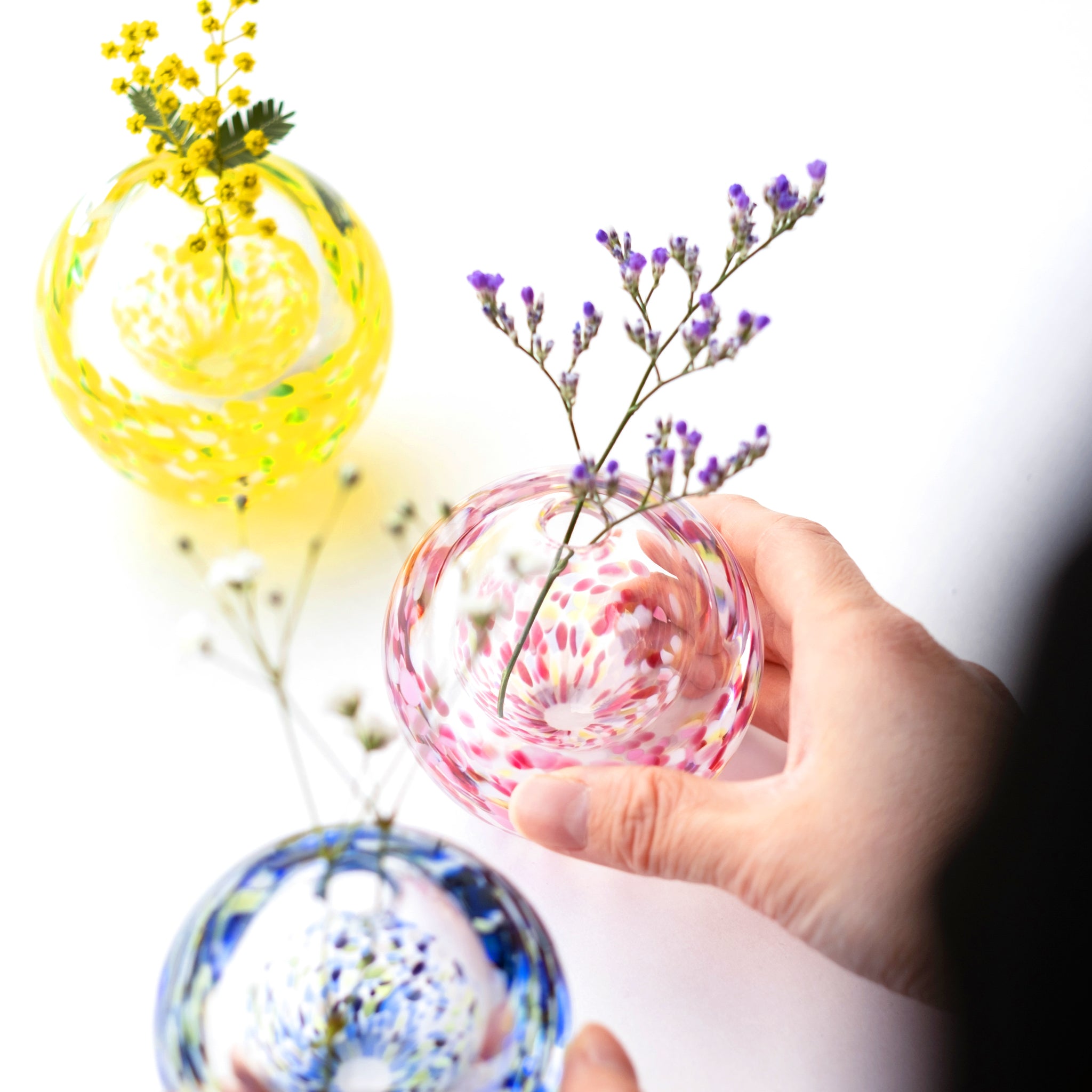 津軽びいどろ にほんの色ふうけい 一輪挿し 舞う桜 切り花が活けられた色違いの花瓶が並んでいる画像