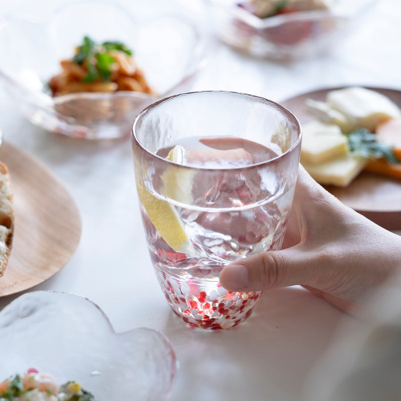 津軽びいどろ 津軽自然色りんご あかりんごタンブラー レモン水が注がれたグラスを手でつかんでいる画像