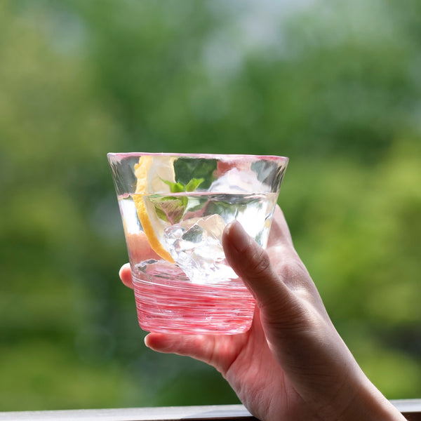 津軽びいどろ 12色のグラス 桜 レモン水が注がれたグラスを手で持っている画像
