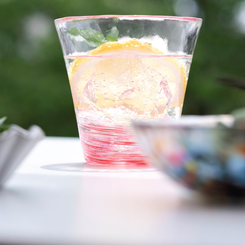 津軽びいどろ 12色のグラス 桜　レモン水が注がれたグラスがテーブルに置かれている画像