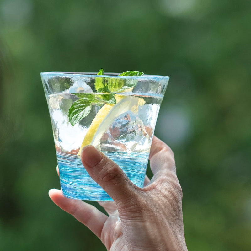 津軽びいどろ 12色のグラス 菜の花 レモン水が注がれたグラスを手で持っている画像